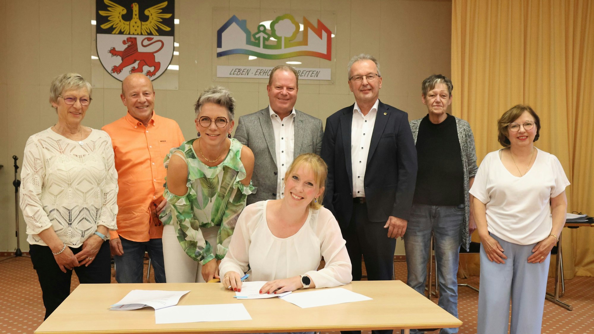 Vertragsunterzeichnung mit Natascha Leienbach (am Tisch) und (v.l.) Liane Prübusch, Reinhard Krumm, Tanja Hacke, Thomas Funke, Rüdiger Gennies, Christine Brach und Marlies Schirp.