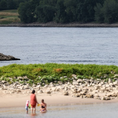 03.07.2025, Düsseldorf: Zwei Frauen und zwei Kinder erfrischen sich im Rhein - an der Stelle, an der am Mittwochabend ein sechs Jahre alter Junge abgetrieben wurde. Die Feuerwehr hat vergeblich nach dem Kind gesucht. Foto: Christoph Reichwein/dpa +++ dpa-Bildfunk +++