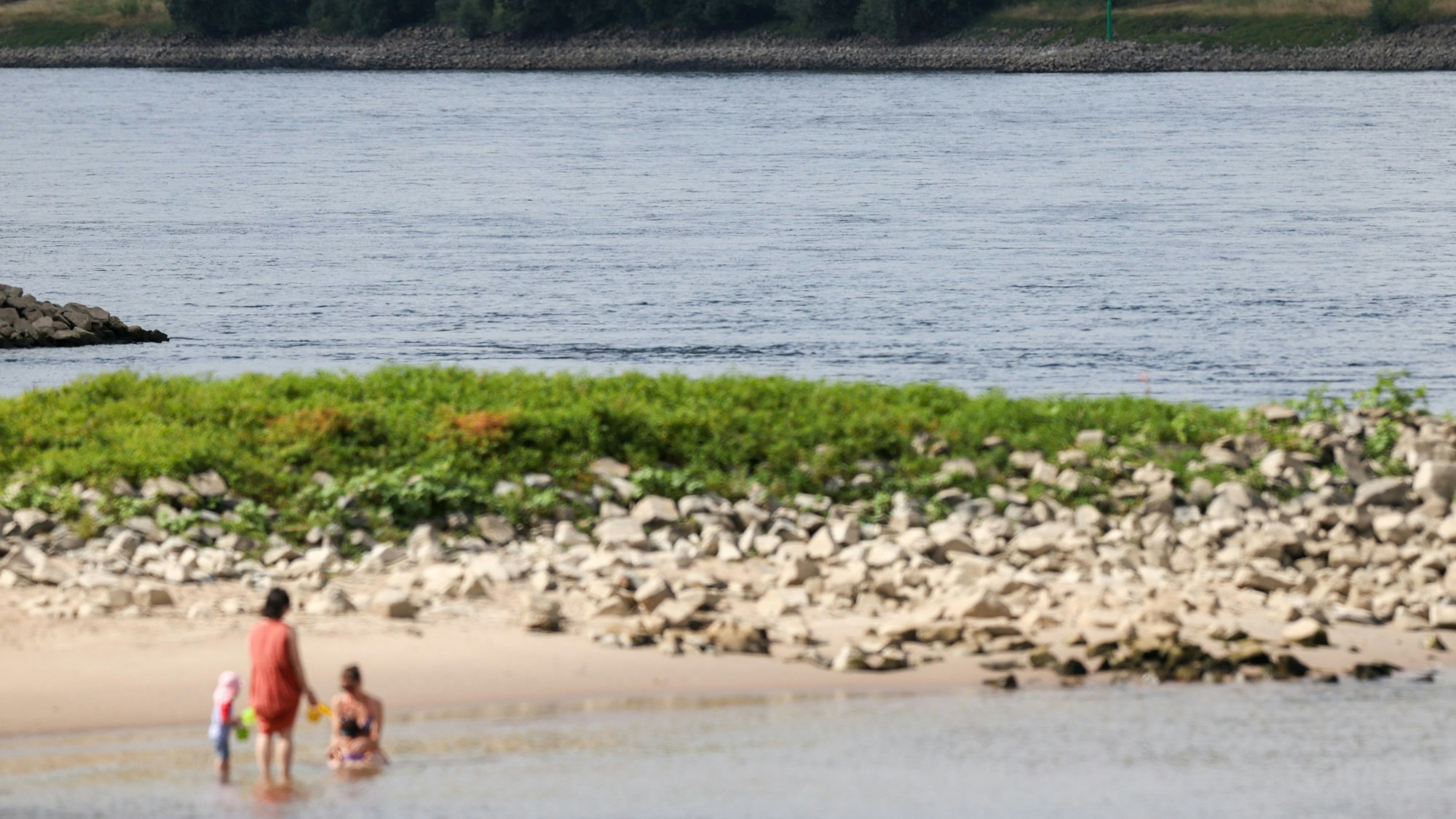 03.07.2025, Düsseldorf: Zwei Frauen und zwei Kinder erfrischen sich im Rhein - an der Stelle, an der am Mittwochabend ein sechs Jahre alter Junge abgetrieben wurde. Die Feuerwehr hat vergeblich nach dem Kind gesucht. Foto: Christoph Reichwein/dpa +++ dpa-Bildfunk +++