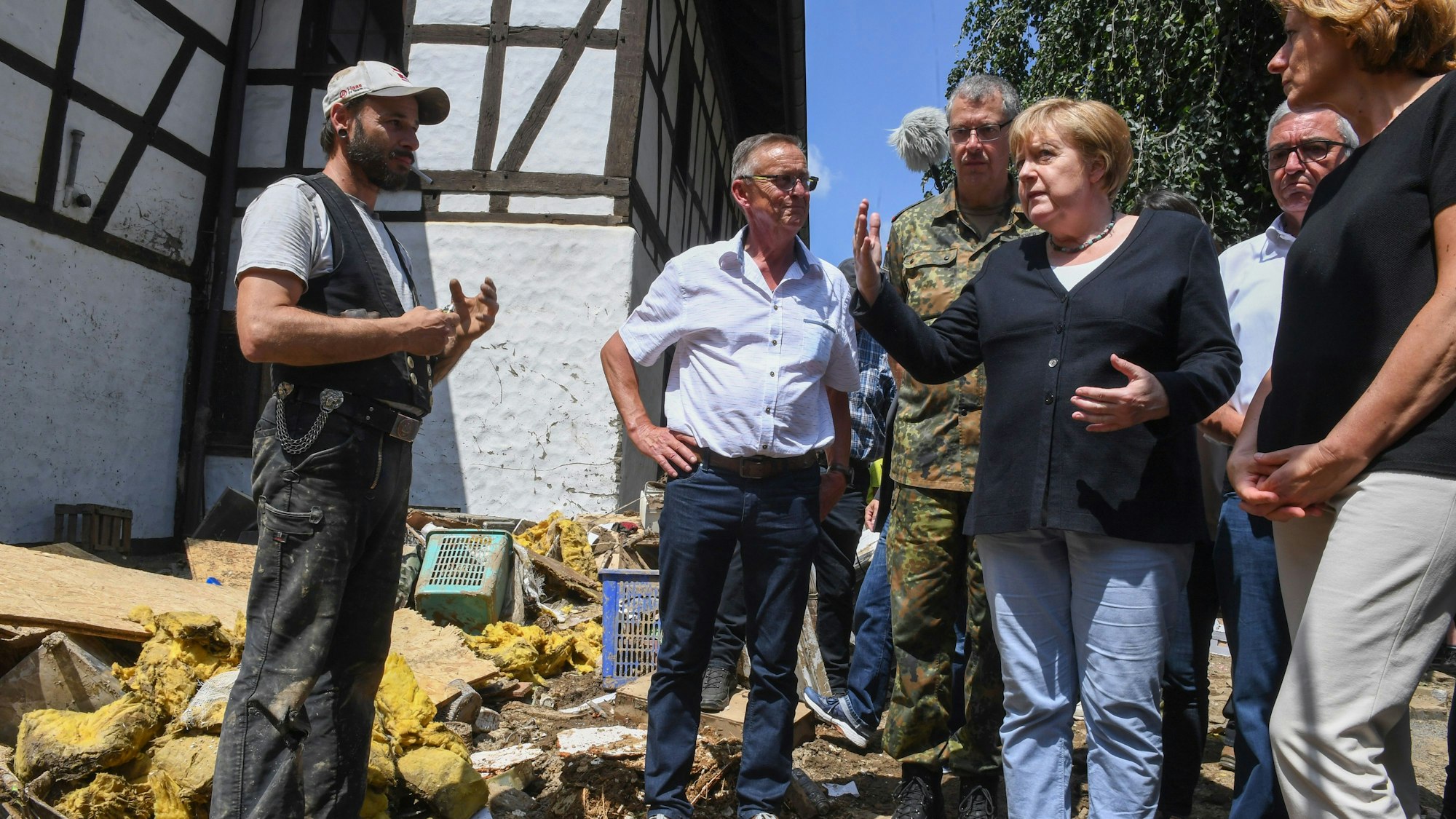 Bundeskanzlerin Angela Merkel (3.v.r.) und Malu Dreyer (r,SPD), Ministerpräsidentin von Rheinland-Pfalz, sprechen mit einem betroffenen Anwohner während ihres Besuchs in dem vom Hochwasser verwüsteten Dorf Schuld bei Bad Neuenahr-Ahrweiler. +++ dpa-Bildfunk +++