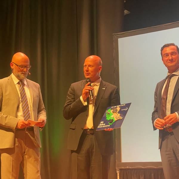 Zu sehen sind Moderator Olly Hahn sowie Frank Rock und Dr. Thomas Wilk auf der Bühne.