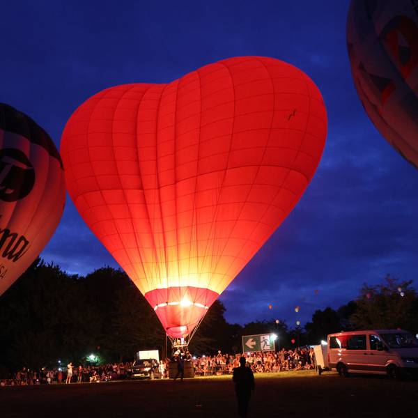 Ein herzförmiger Heißluftballon glüht rot im Dunkeln.