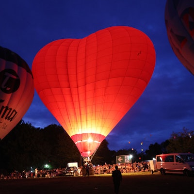 Ein herzförmiger Heißluftballon glüht rot im Dunkeln.