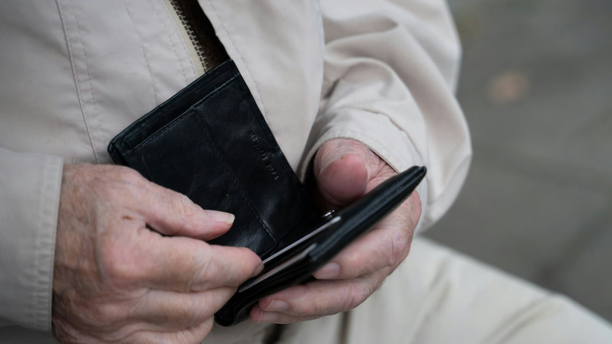 Ein Rentner hält sein Portemonnaie in der Hand.
