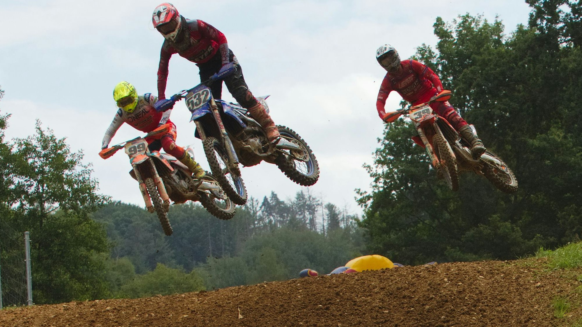 Drei Motocrossfahrer springen mit ihren Maschinen in die Luft.
