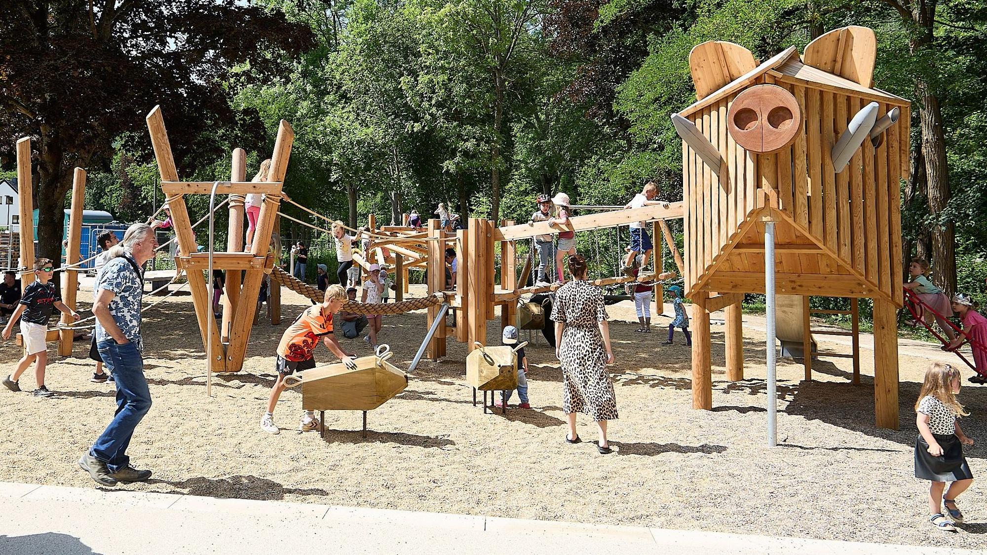 Kinder spielen auf dem neuen Spielplatz im Kurpark in Gemünd. Die Spielgeräte sind aus Holz gestaltet.