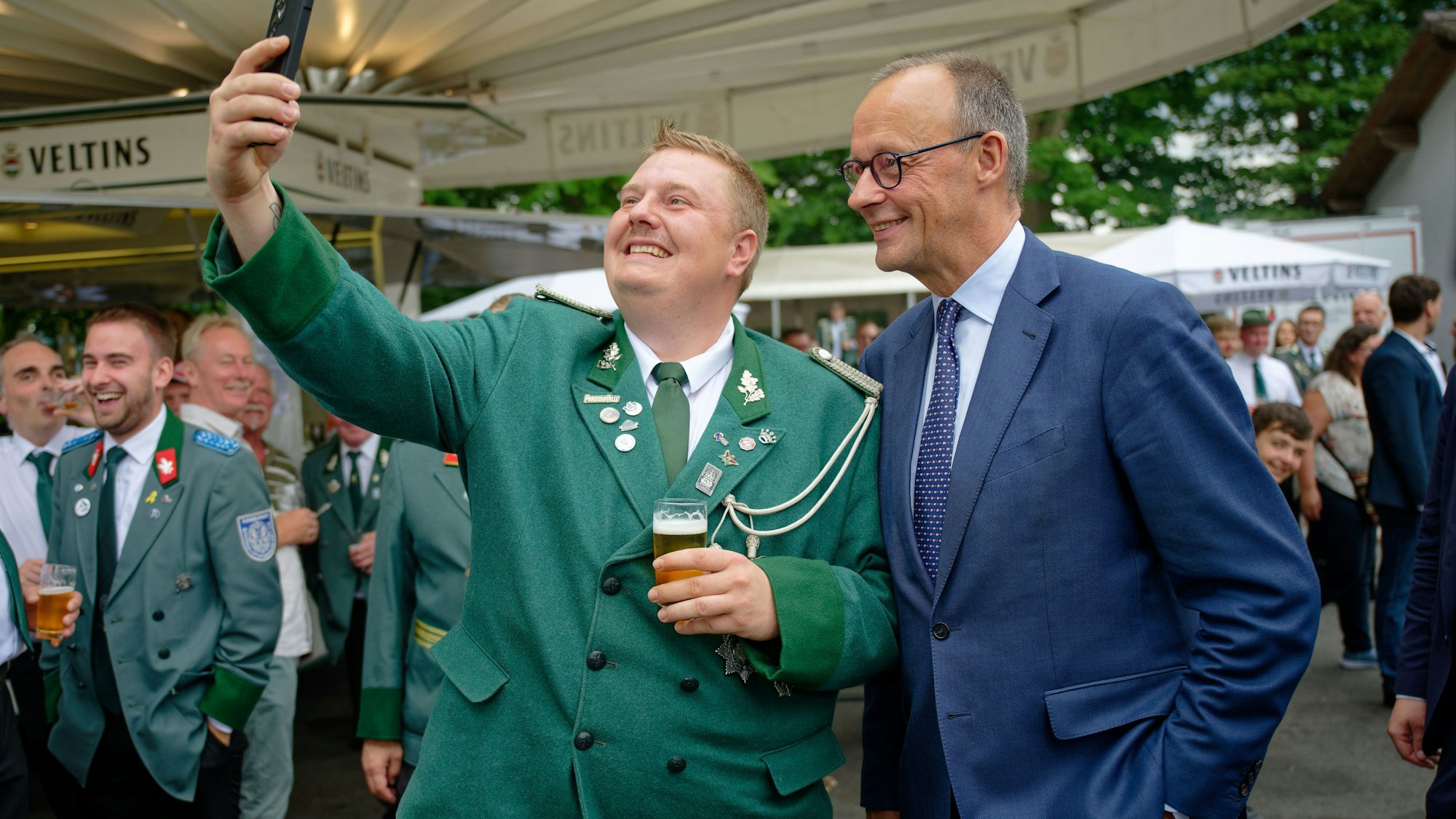 Bundeskanzler Friedrich Merz (CDU) und ein Besucher machen beim Schützenfest der St. Stephanus Schützenbruderschaft Niedereimer an der Schützenhalle ein Selfie.