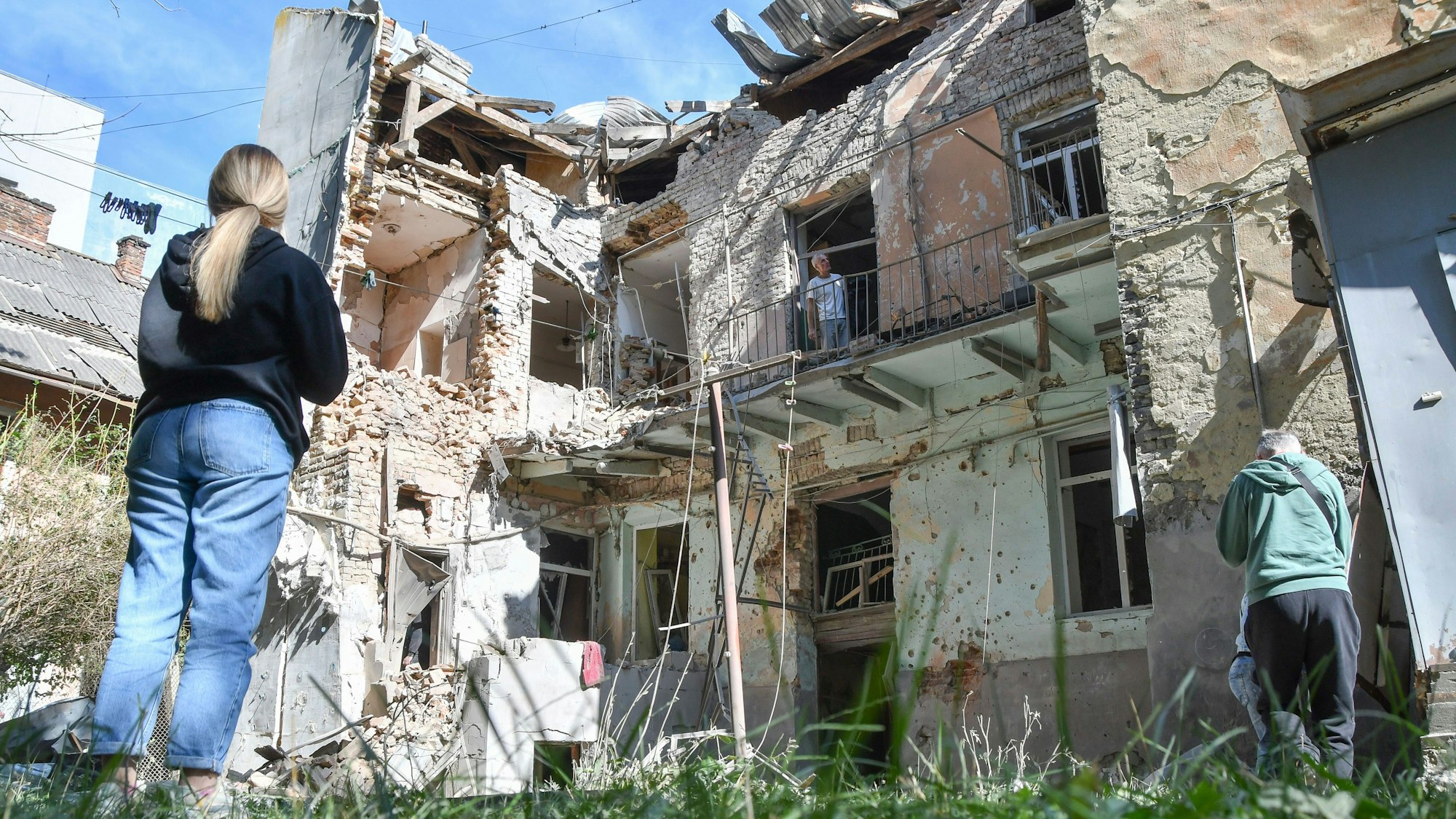 Menschen betrachten ein beschädigtes Wohnhaus nach einem russischen Luftangriff in Lwiw.