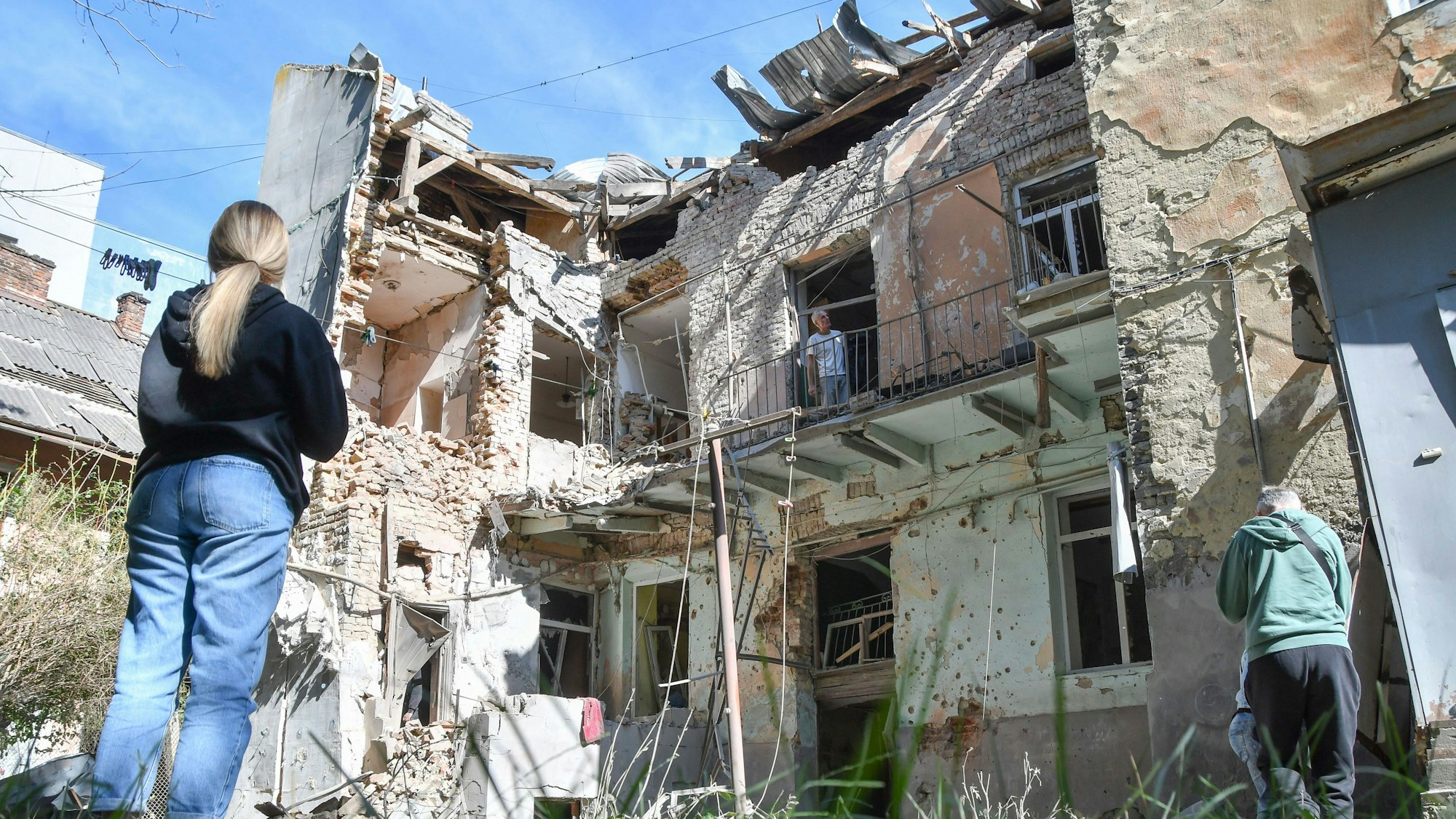 12.07.2025, Ukraine, Lwiw: Menschen betrachten ein beschädigtes Wohnhaus nach einem russischen Luftangriff in Lwiw. Foto: Mykola Tys/AP/dpa +++ dpa-Bildfunk +++