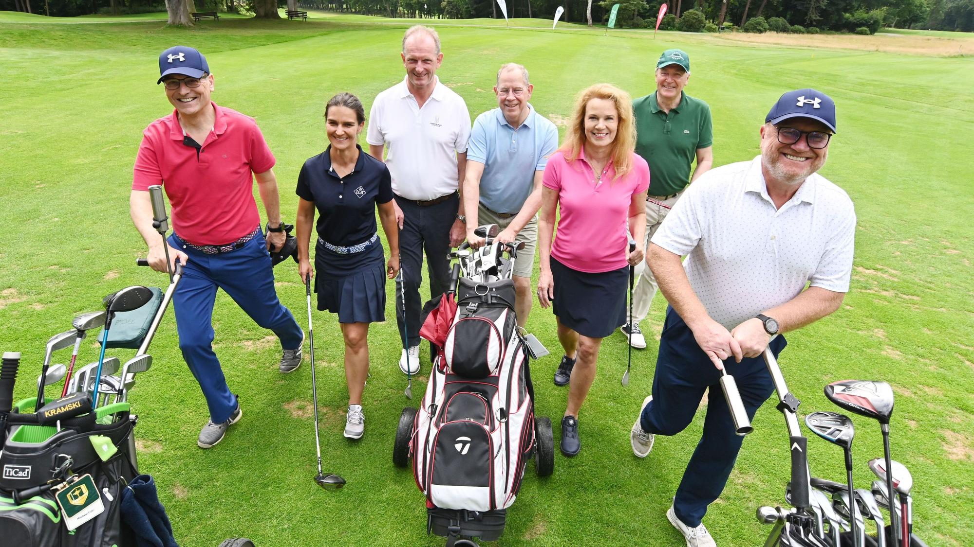 Mehrere Menschen gehen über einen Golfplatz.
