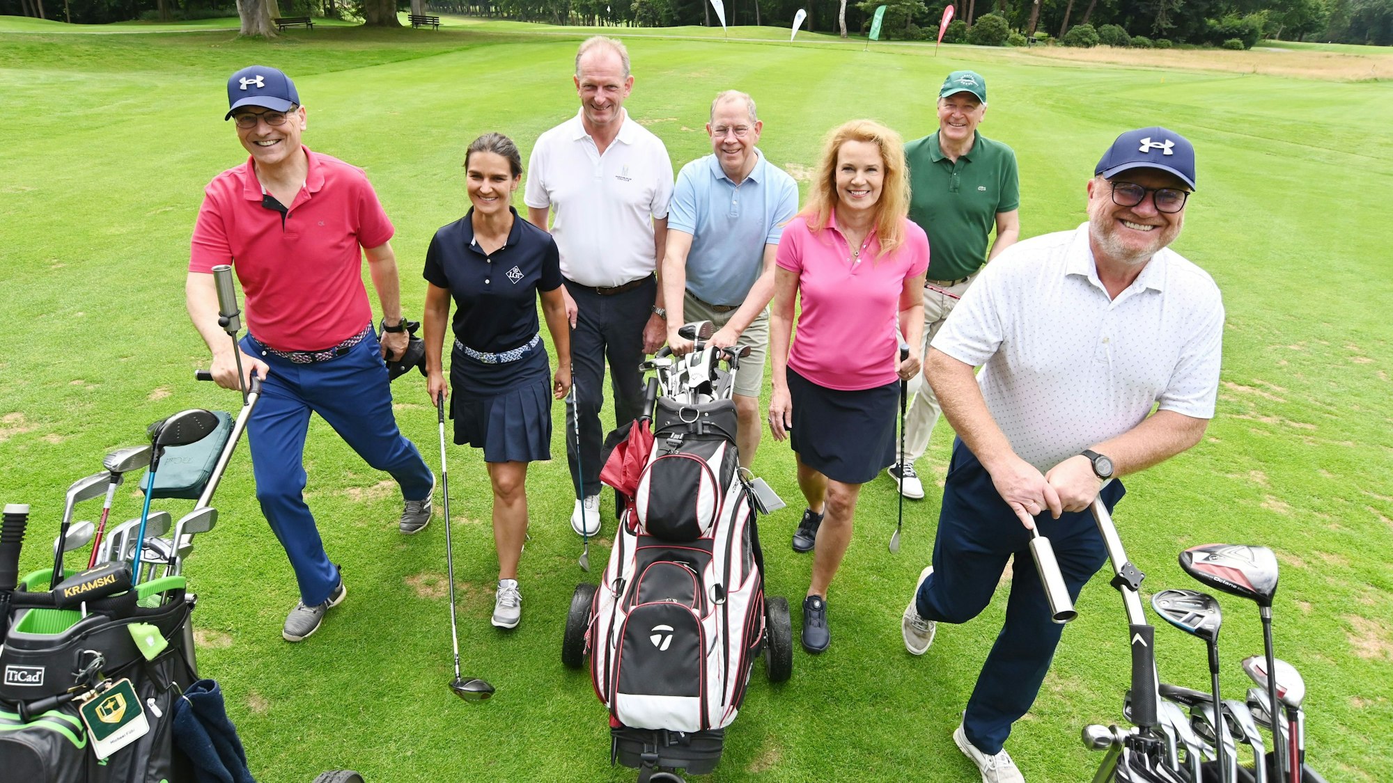 Mehrere Menschen gehen über einen Golfplatz.