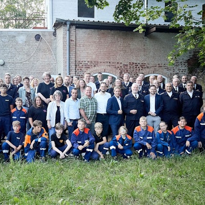 Eine Gruppe Erwachsene und Kinder posiert auf einem Rasen für ein Foto.