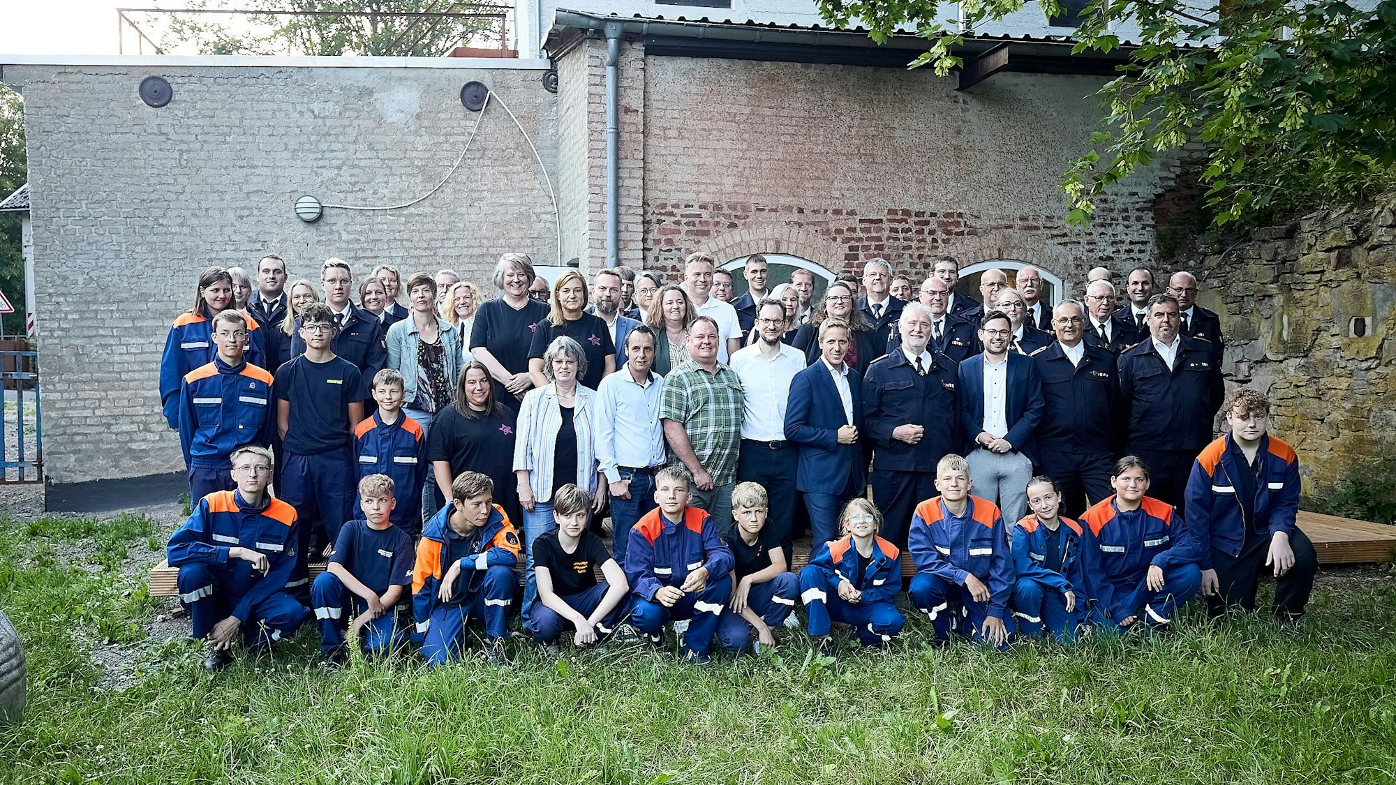 Eine Gruppe Erwachsene und Kinder posiert auf einem Rasen für ein Foto.