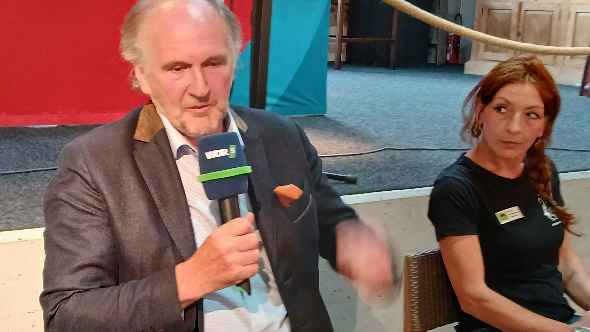 Schäfer Georg Bungart spricht ins Mikrofon, Silke Roth schaut ihn dabei an.