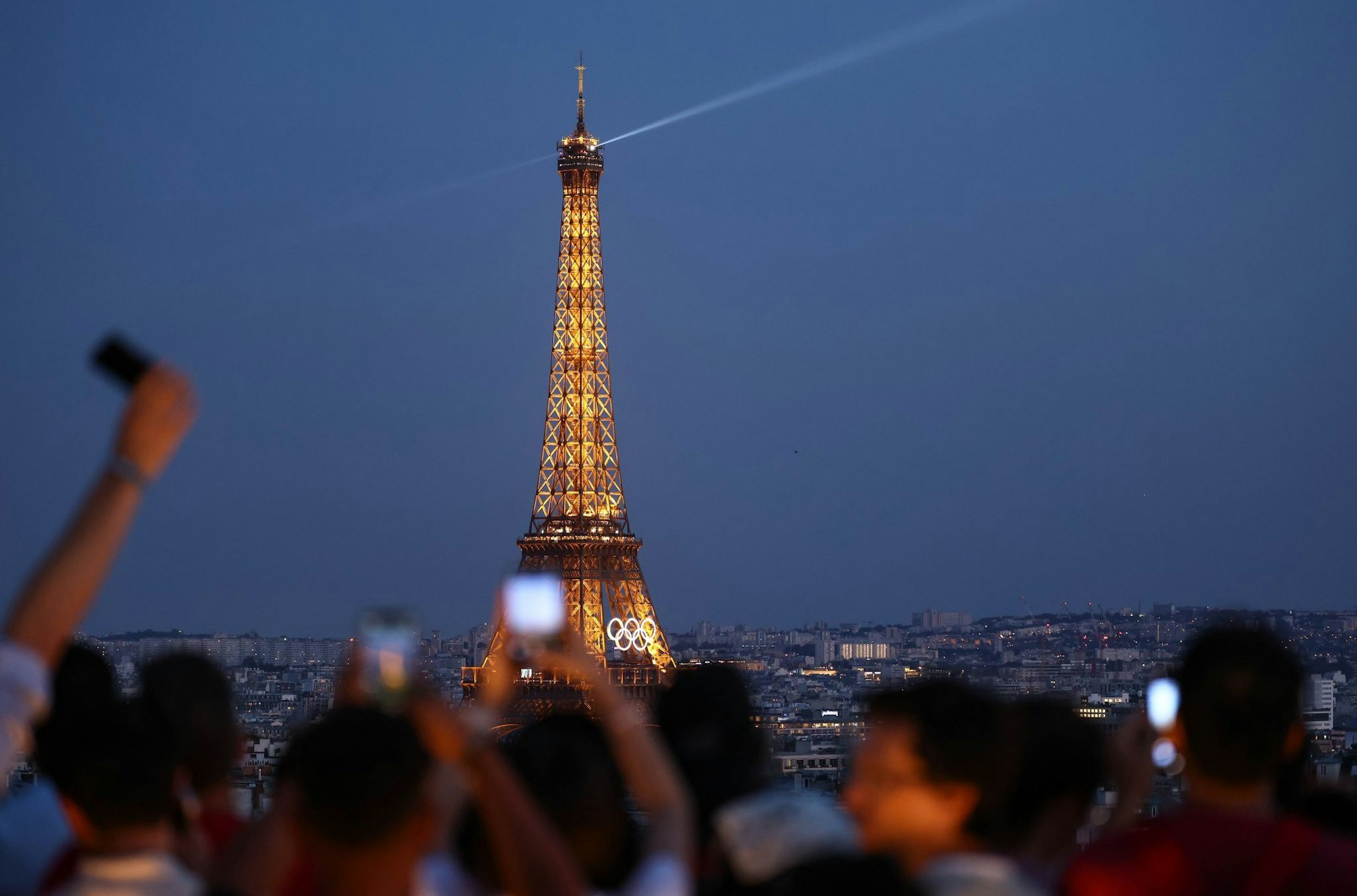 Paris im Sommer 2024 - besonders beliebt: Touristen fotografieren den Eiffelturm mit den Olympischen Ringen von der Terrasse des Triumphbogens. (Archivbild)