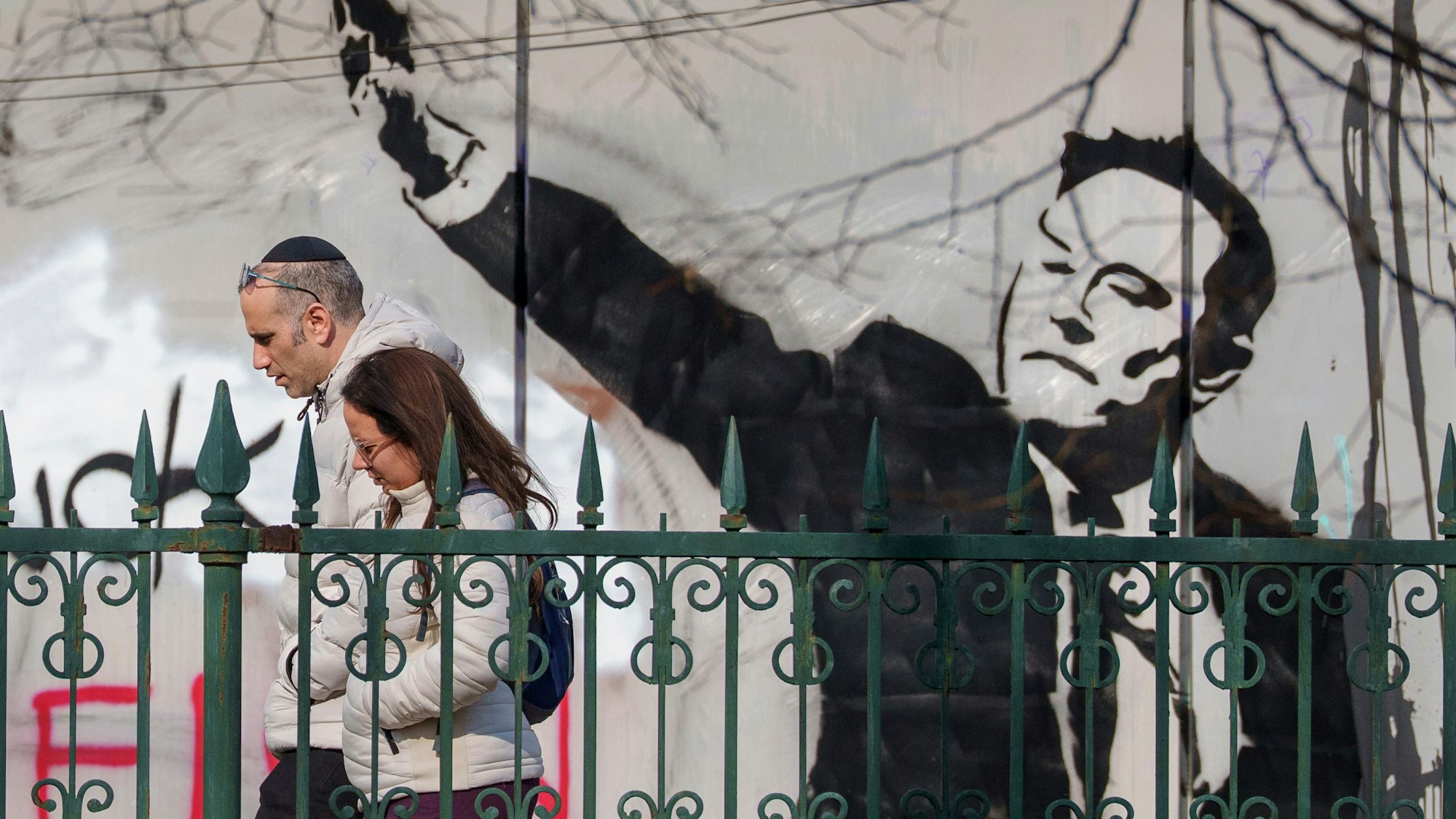 Menschen gehen in Bukarest an einem Wandgemälde vorbei, das Tech-Milliardär Elon Musk mit einer Hitlergruß-ähnlichen Geste zeigt. Unternehmen in Deutschland ziehen sich zumindest teilweise von Musks Plattform X zurück. (Archivbild)