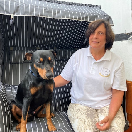 Eine Frau sitzt mit ihrem Hund zusammen in einem Strandkorb.