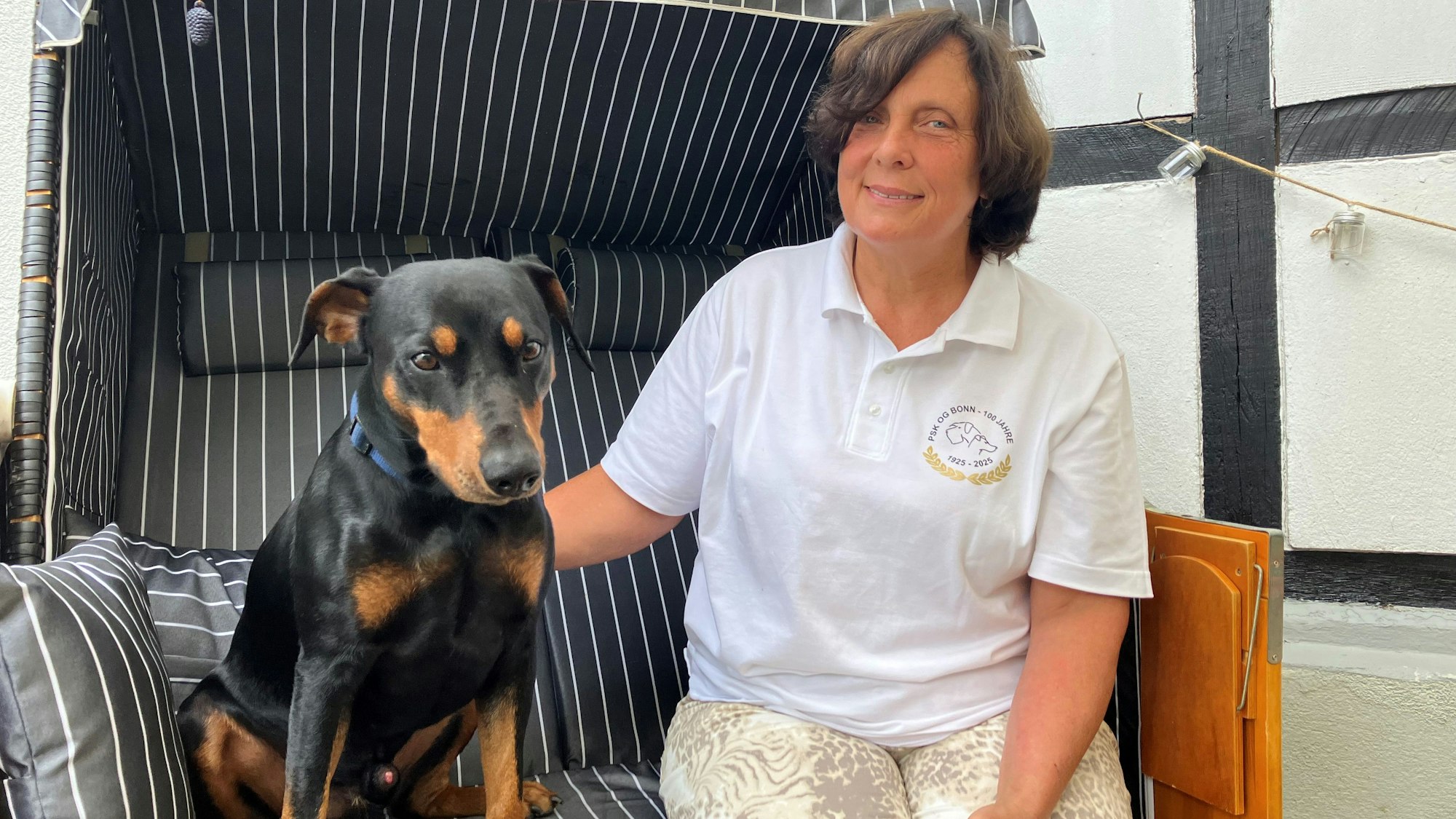 Eine Frau sitzt mit ihrem Hund zusammen in einem Strandkorb.