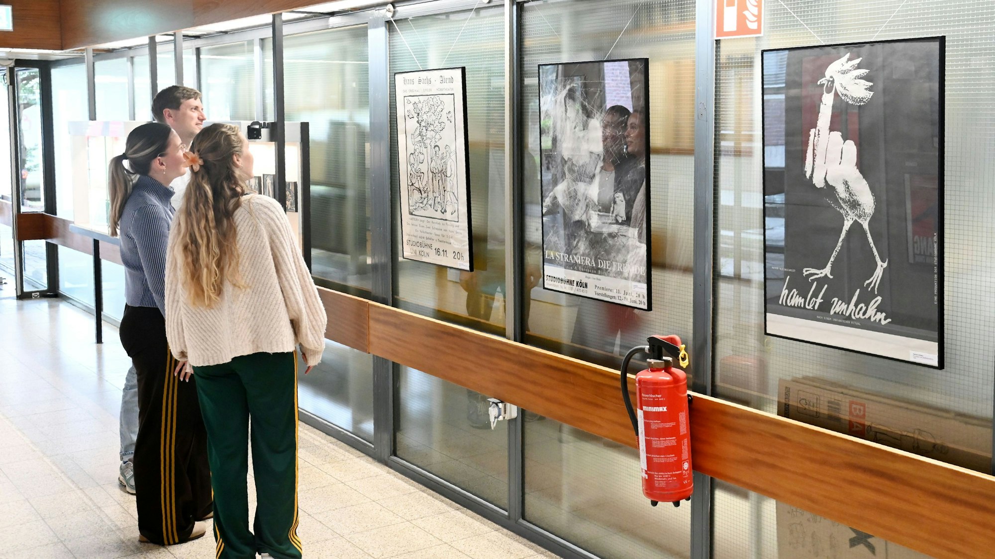 Das Bild zeigt Studentinnen und Studenten der Universität zu Köln, wie sie sich ein Plakat anschauen.