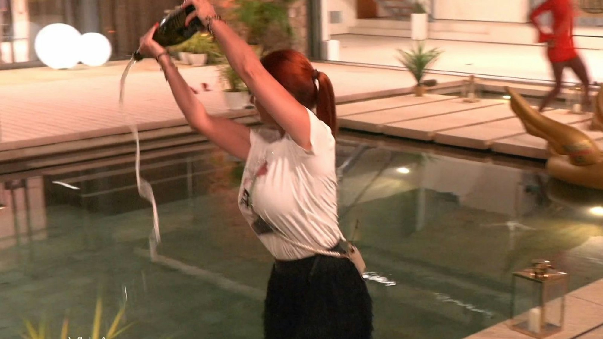 „Da habt ihr euer Entertainment“: Als Rache für ihren Rauswurf kippt Bettie Ballhaus 3.000 Euro teuren Champagner in den Pool. (Bild: Joyn)