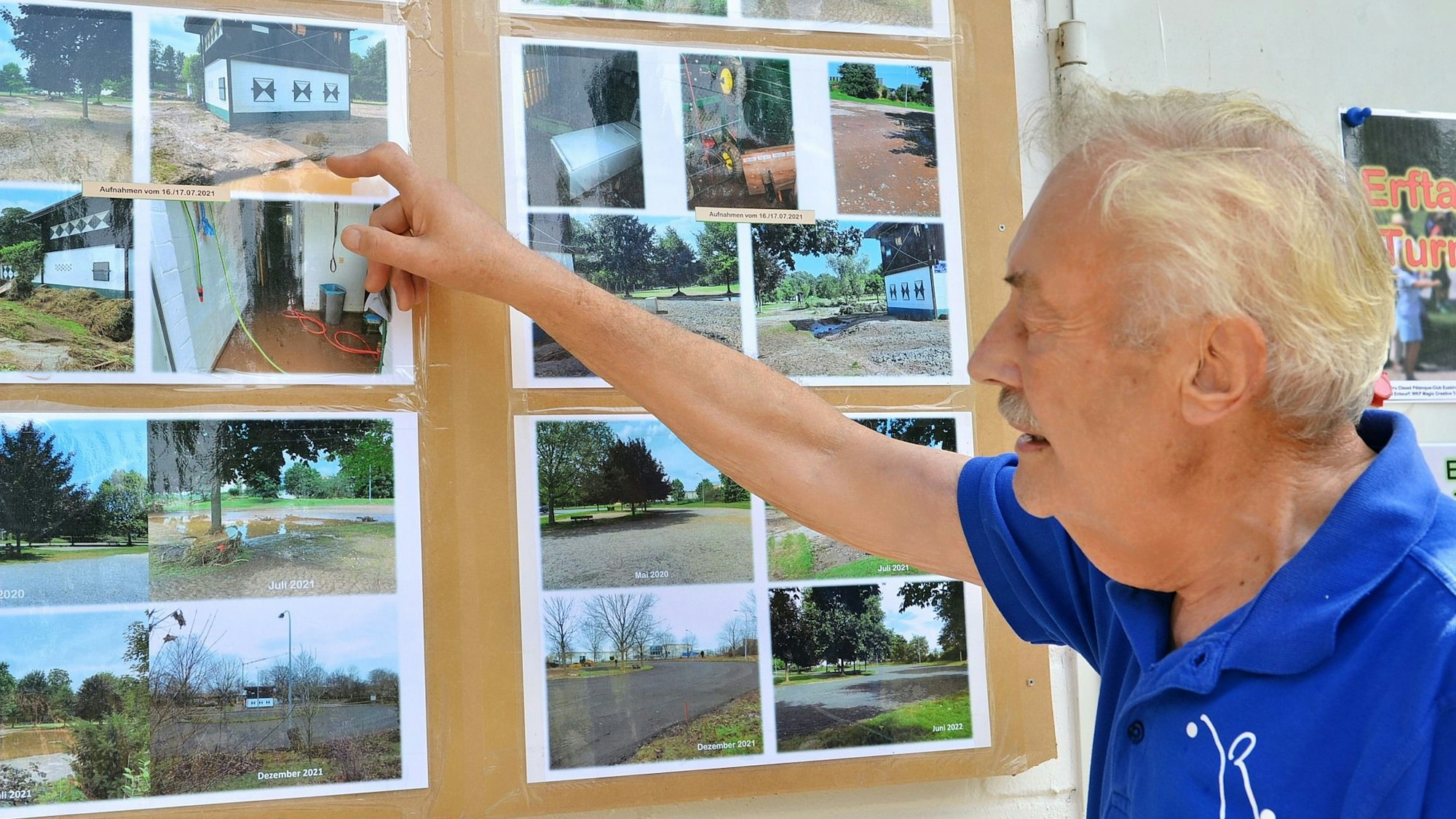 Wolfgang Vieweg zeigt auf Aufnahmen der Flutkatastrophe 2021, die an einer Wand hängen.