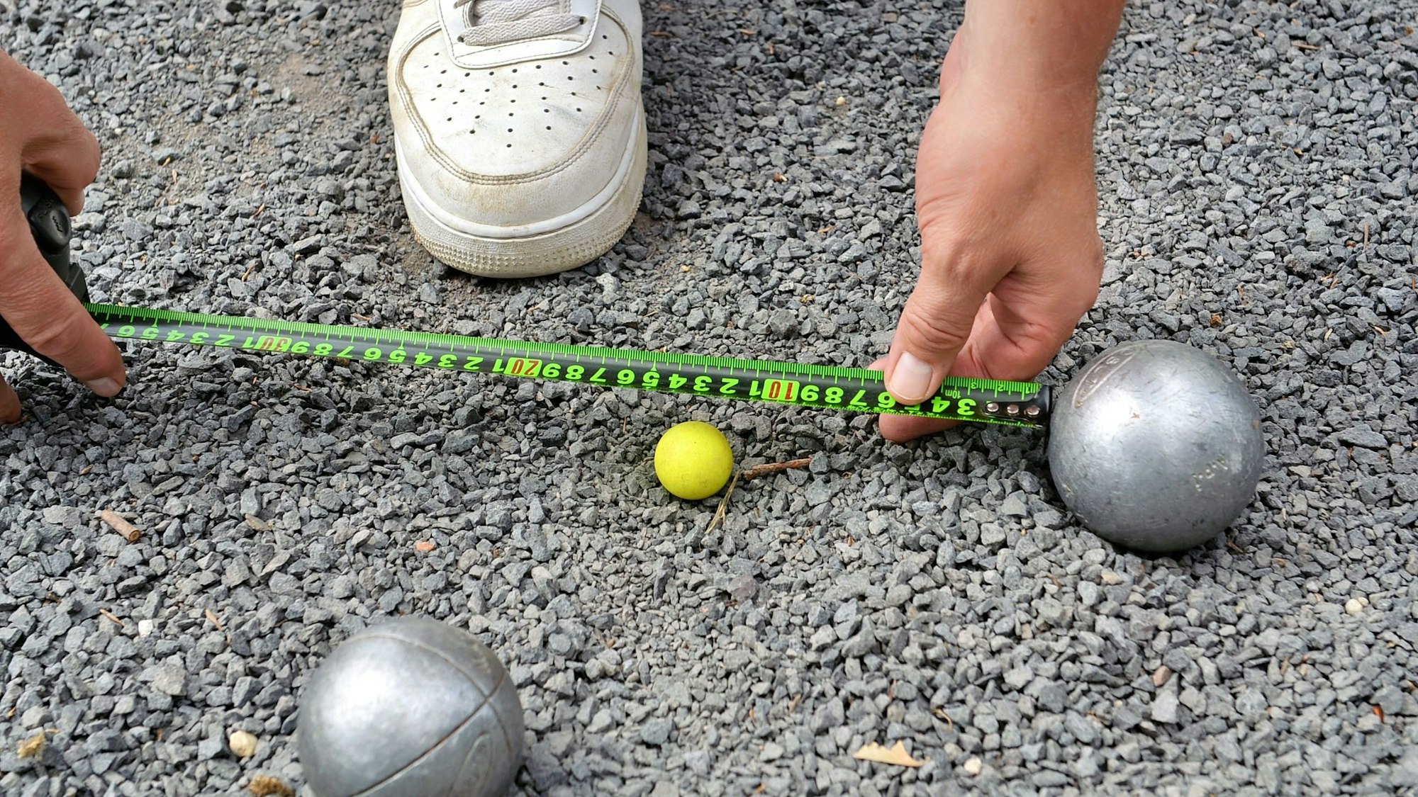 Nahaufnahme: Der Abstand vom sogenannten „Schweinchen“ zu einer Boule-Kugel wird abgemessen.