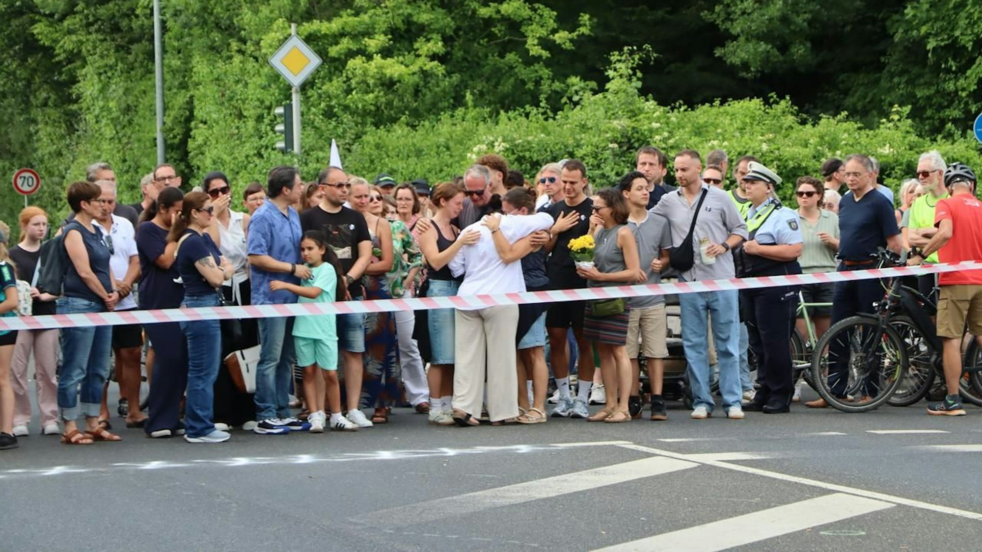 Auf dem Bild sind Trauernde zu sehen, die sich gegenseitig umarmen.