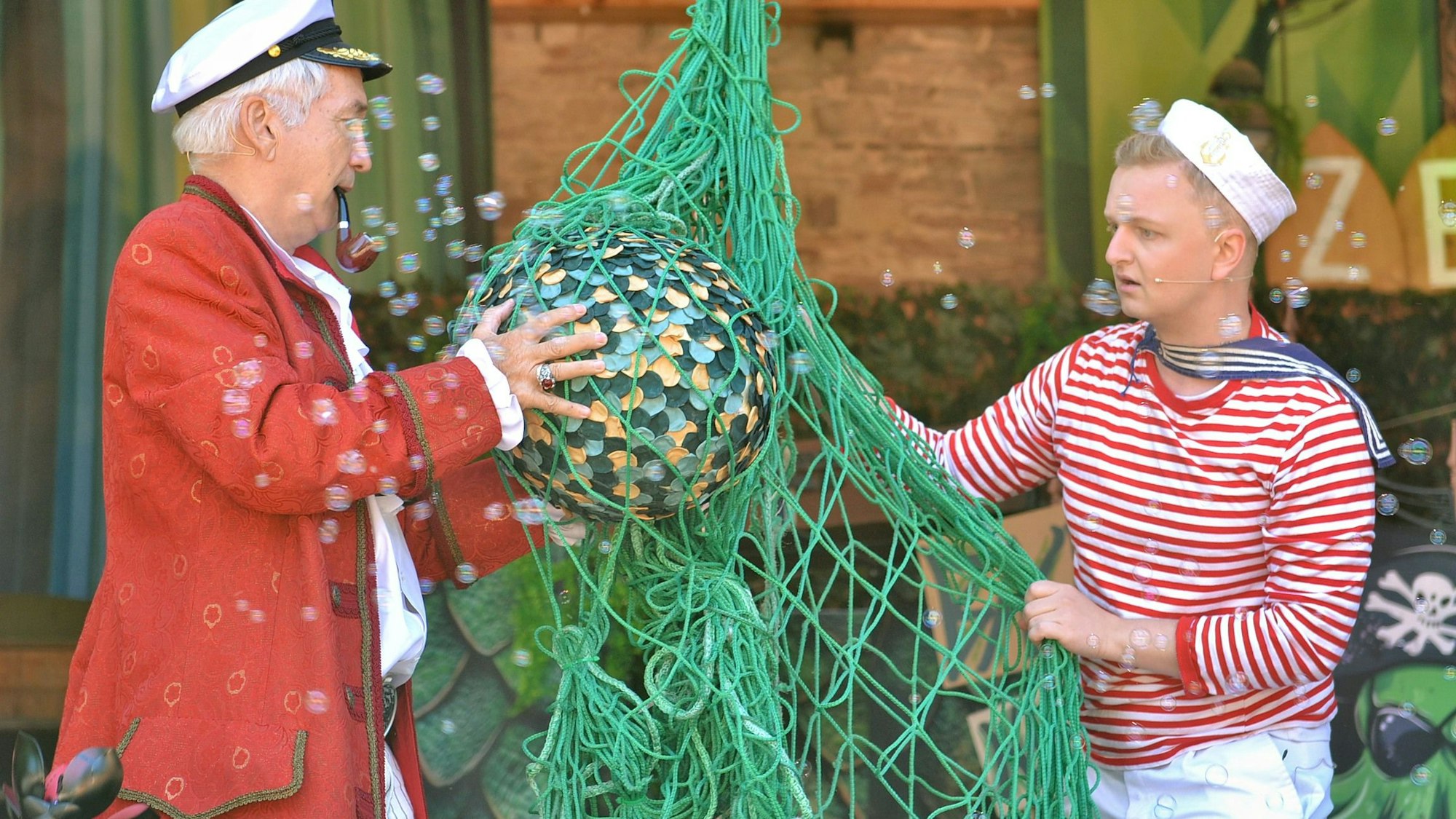 Zwei Männer halten ein Netz in den Händen, in denen sich ein kugelförmiger Gegenstand befindet.
