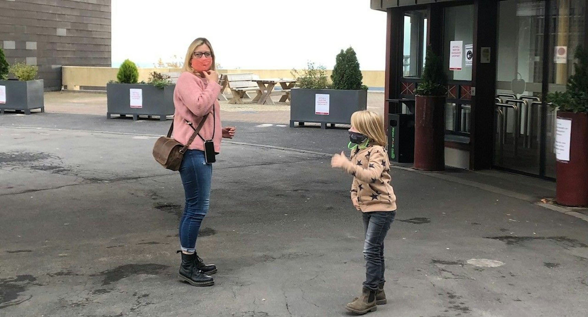 Frau und Kind mit Maske vor dem Hotel