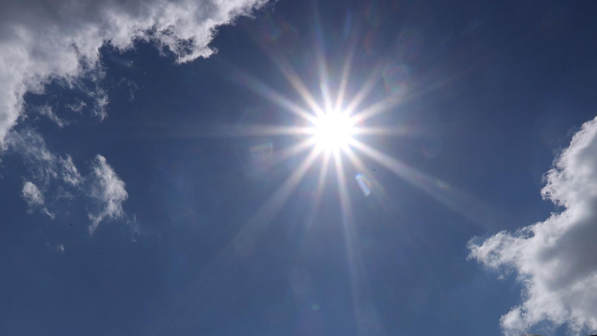 Die Sonne lugt zwischen zwei Wolken hervor.