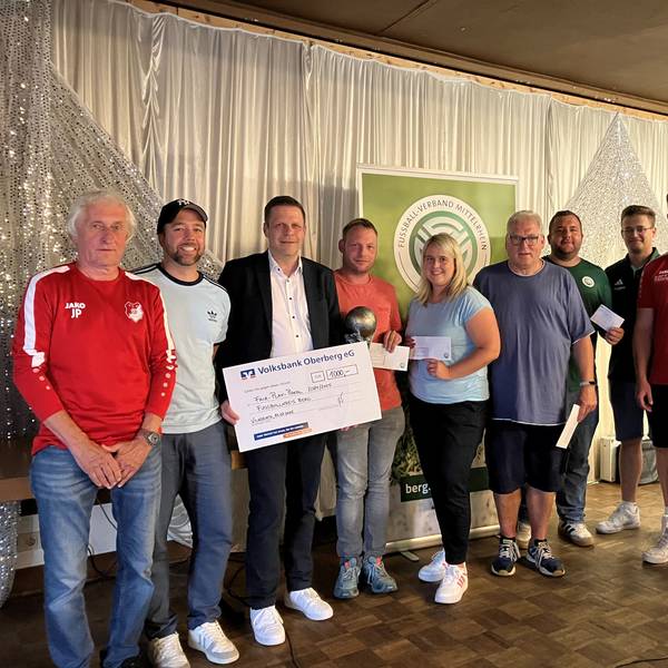 Ein Gruppenfoto verschiedener Vertreter von Fußballvereinen und einem Mitarbeiter der Volksbank, der einen Scheck in der Hand hält.