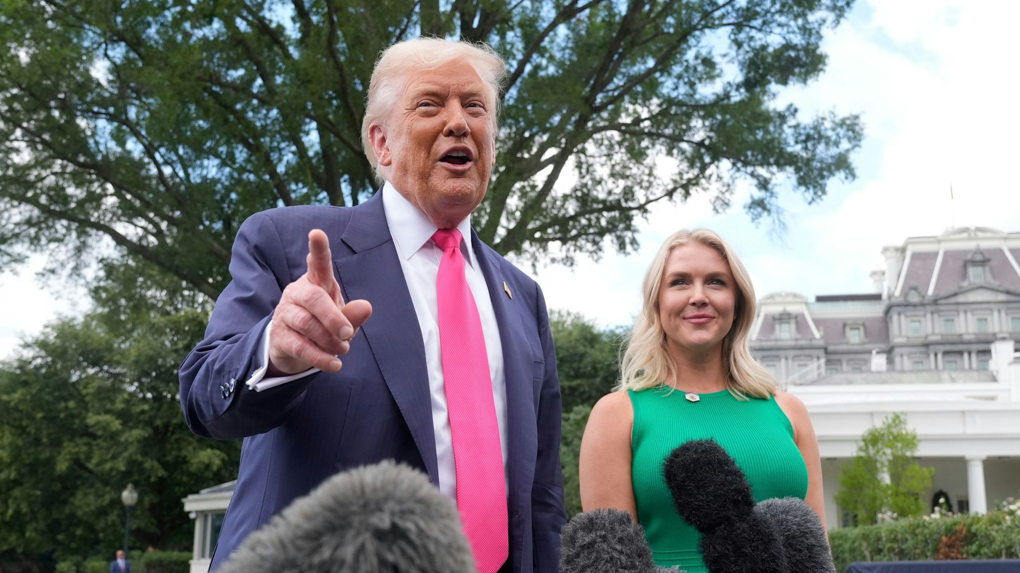 US-Präsident Donald Trump spricht zu den Medien, als er das Weiße Haus verlässt, während die Pressesprecherin des Weißen Hauses, Karoline Leavitt, zusieht.