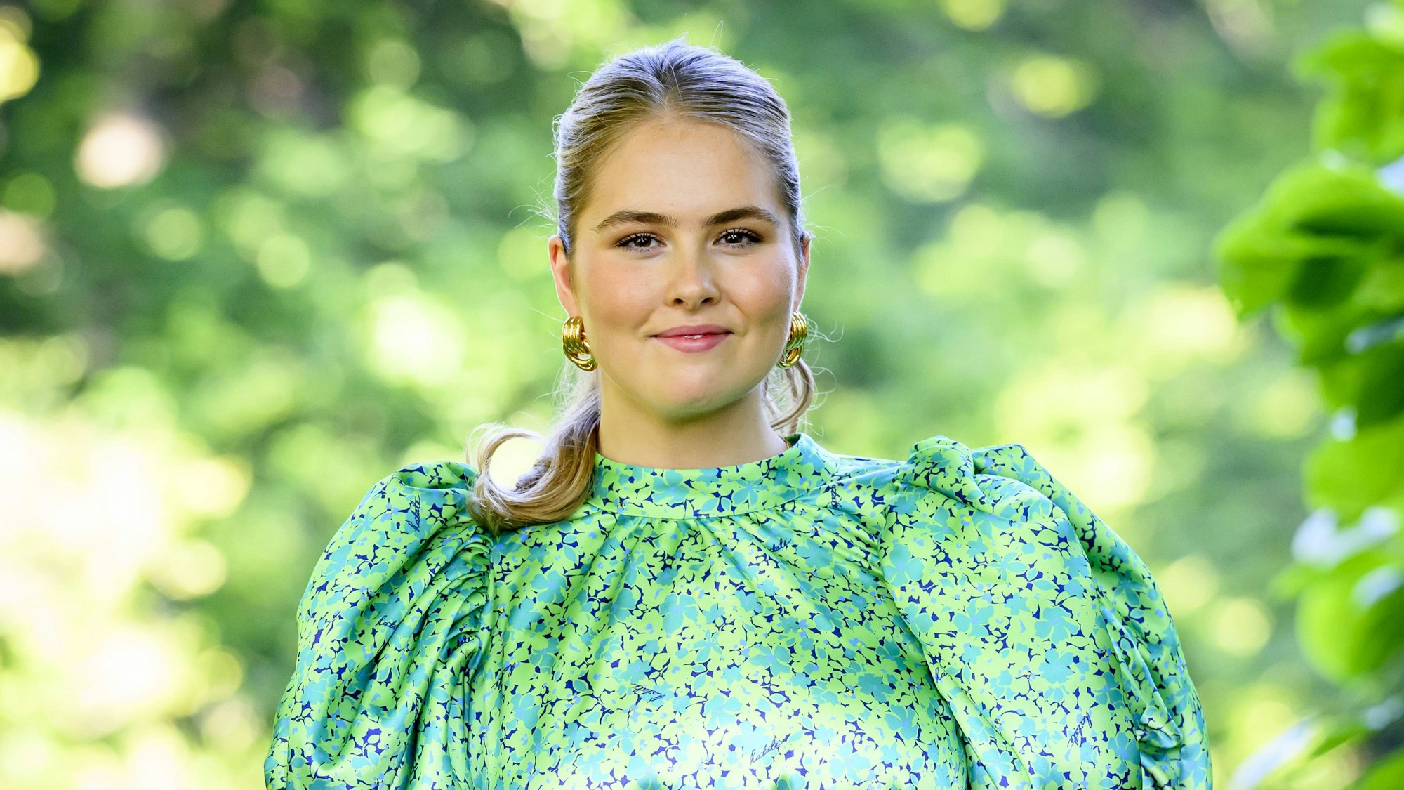 Prinzessin Amalia zeigt sich im sommerlichen Look mit grün-blauem Blumenkleid und goldenen Creolen – aufgenommen beim traditionellen Fotoshooting der niederländischen Königsfamilie in Den Haag.