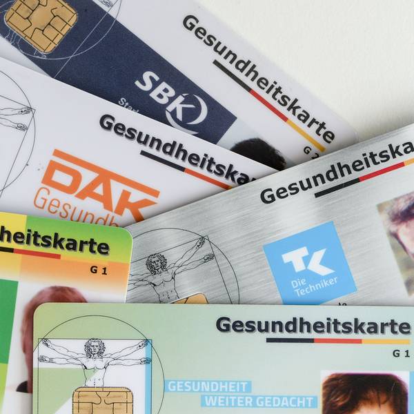Gesundheitskarten verschiedener Krankenkassen liegen auf einem Tisch.