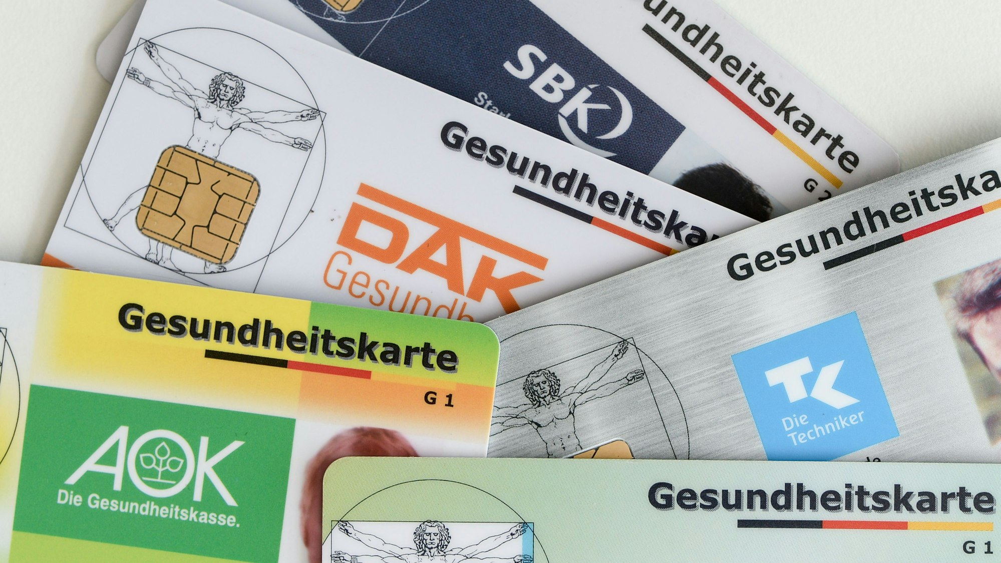 Gesundheitskarten verschiedener Krankenkassen liegen auf einem Tisch.