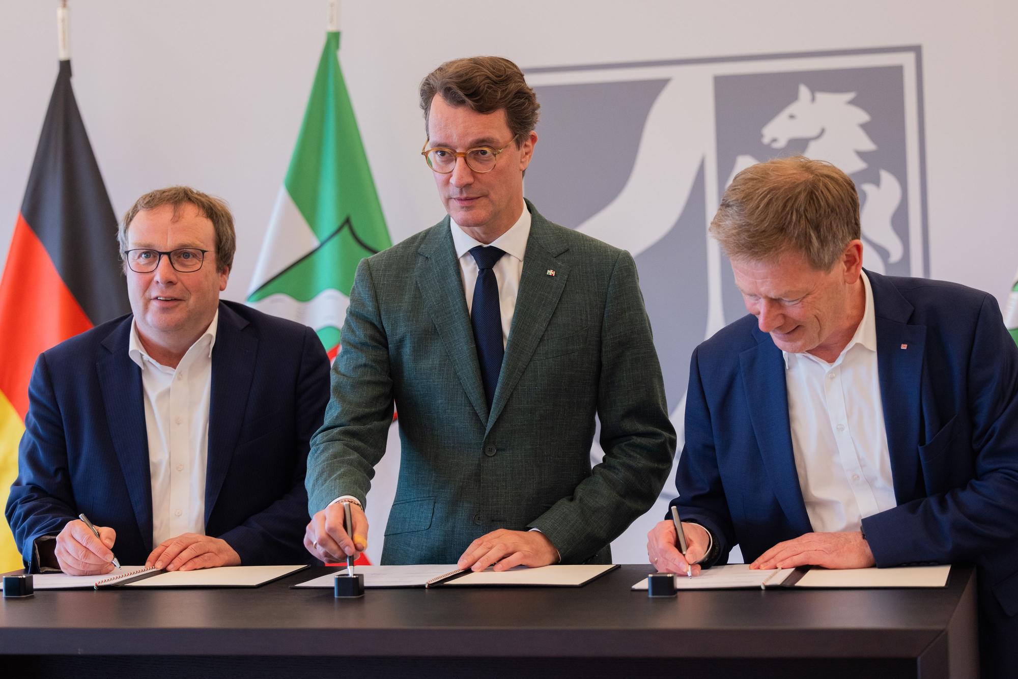 Bahnchef Richard Lutz (r.), Ministerpräsident Hendrik Wüst und NRW-Verkehrsminister Oliver Krischer unterzeichnen am Dienstag in Düsseldorf eine Kooperationsvereinbarung.