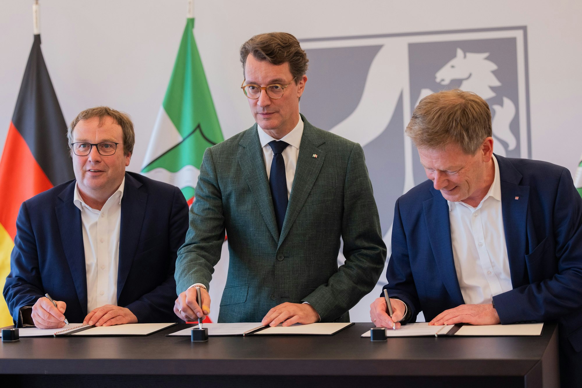 Bahnchef Richard Lutz (r.), Ministerpräsident Hendrik Wüst und NRW-Verkehrsminister Oliver Krischer unterzeichnen am Dienstag in Düsseldorf eine Kooperationsvereinbarung.