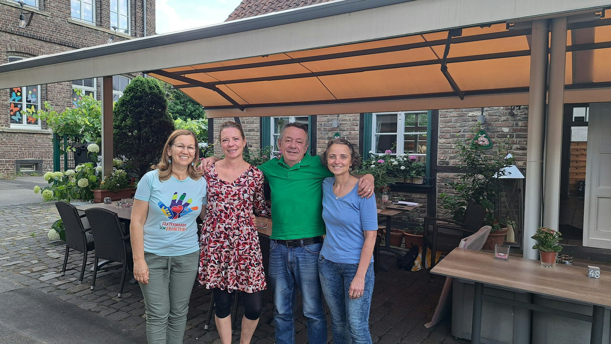 Drei Frauen und ein Mann stehen im Innenhof eines Restaurants.
