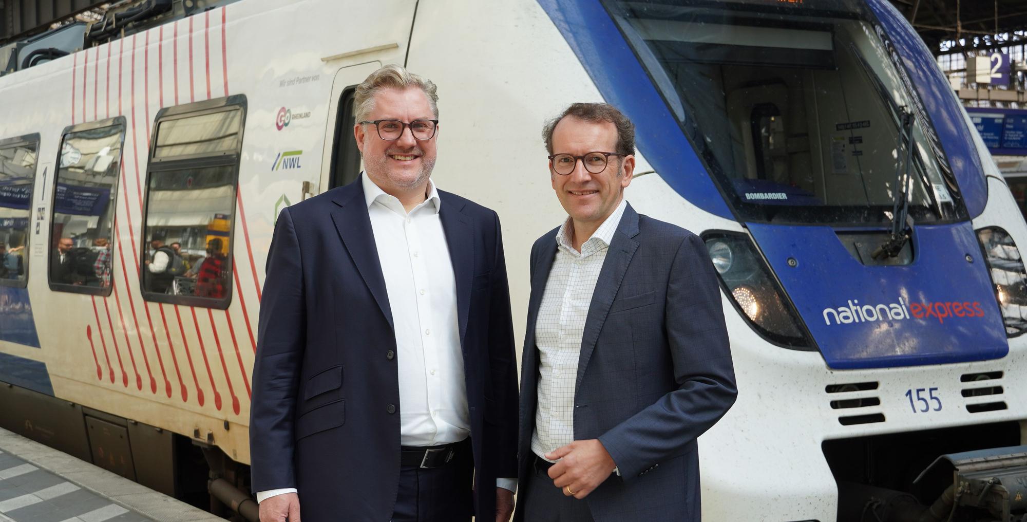 Tobias Krogmann und Michael Hetzer (rechts), die Geschäftsführer des Eisenbahnverkehrsunternehmens National Express, stehen im Juli 2025 vor einem Regionalzug im Kölner Hauptbahnhof.
