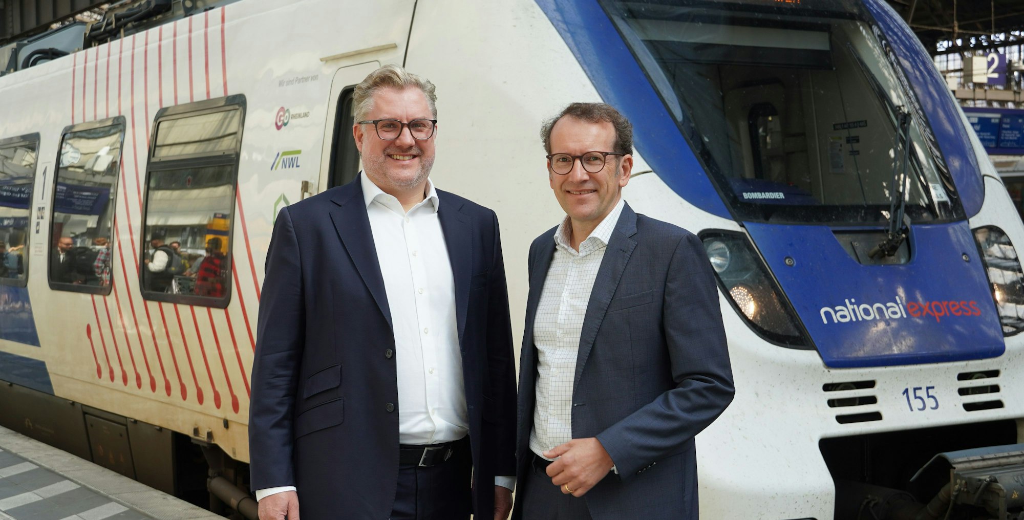 Tobias Krogmann und Michael Hetzer (rechts), die Geschäftsführer des Eisenbahnverkehrsunternehmens National Express, stehen im Juli 2025 vor einem Regionalzug im Kölner Hauptbahnhof.