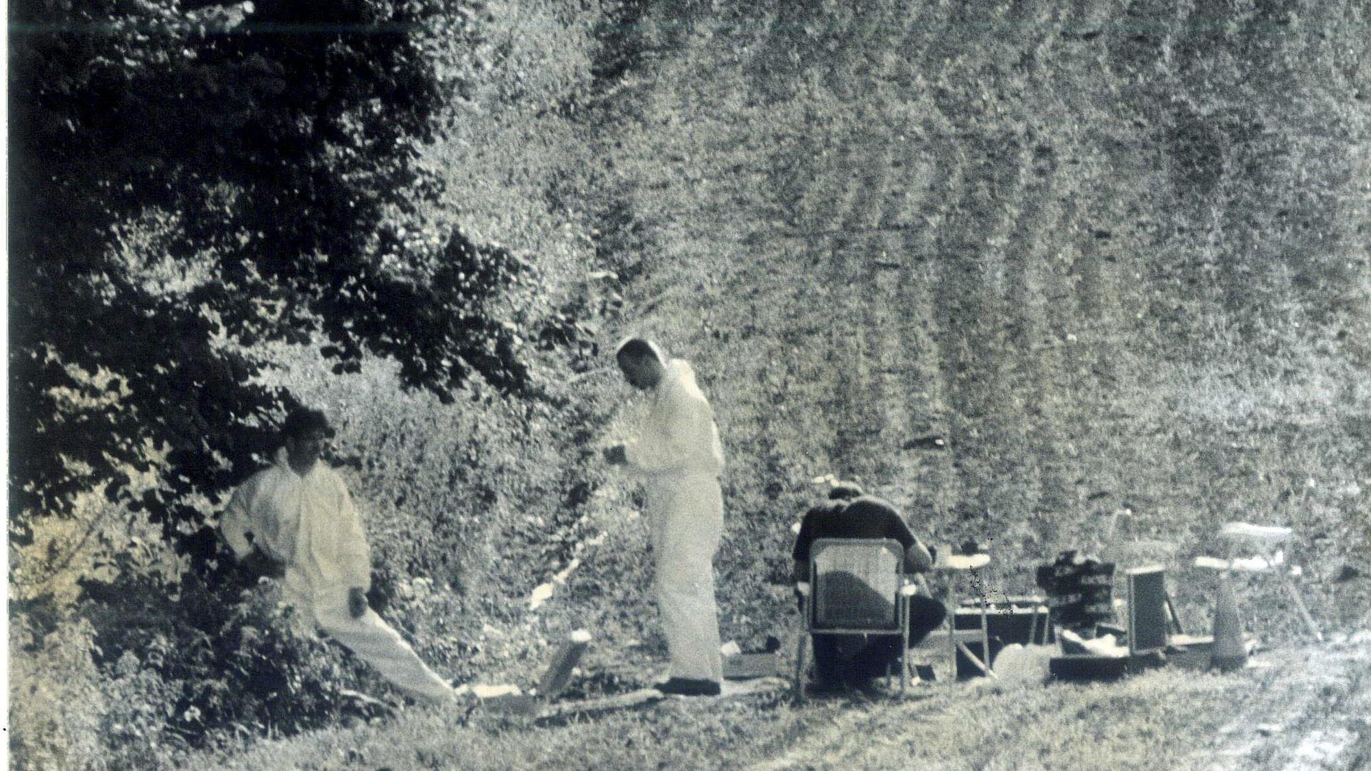 Der Tatort 1995: Zwei Männer in Schutzanzügen auf einem Feld, daneben sitzt ein weiterer Mann an einem Tisch mit Stühlen.