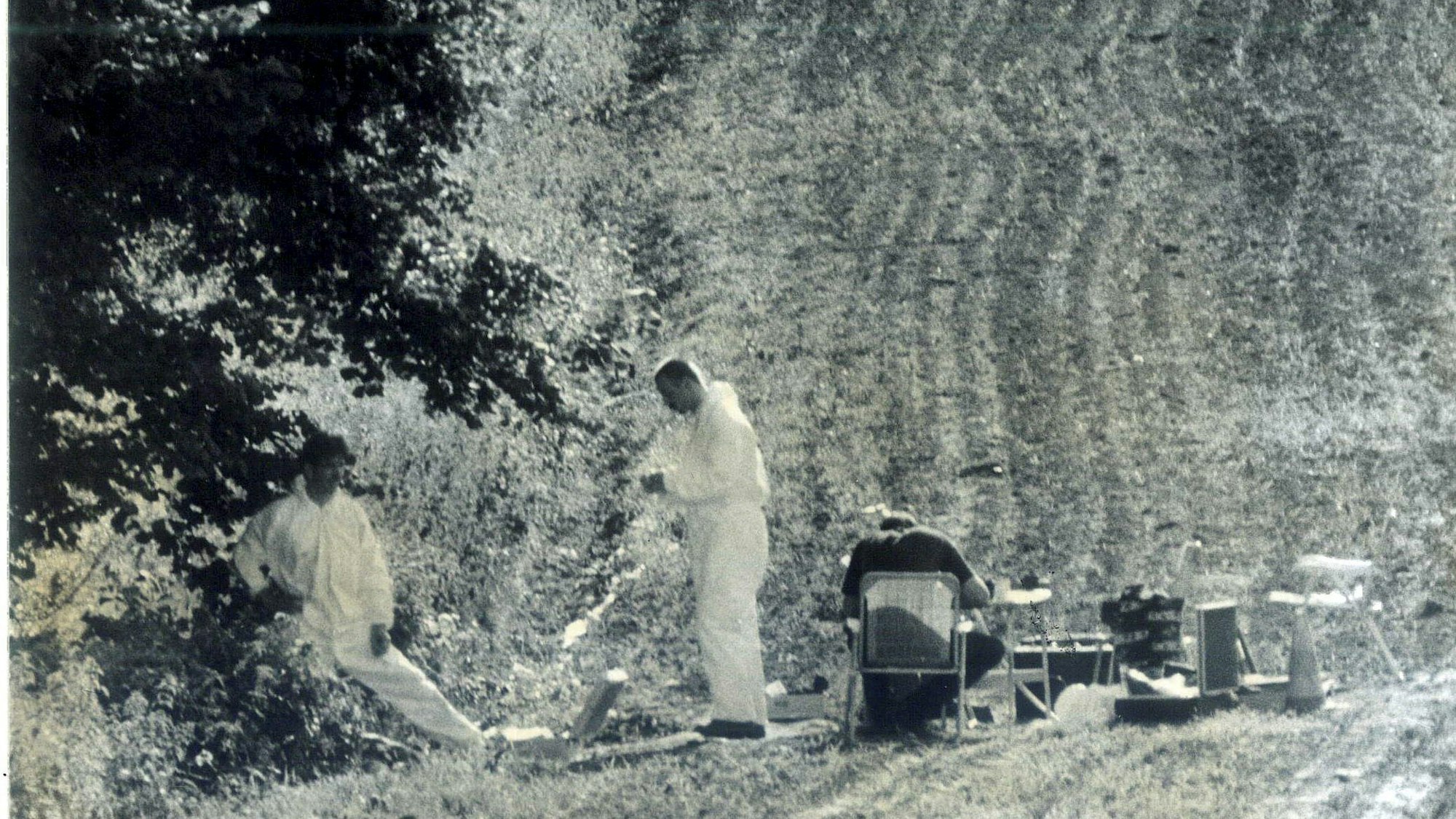 Der Tatort 1995: Zwei Männer in Schutzanzügen auf einem Feld, daneben sitzt ein weiterer Mann an einem Tisch mit Stühlen.