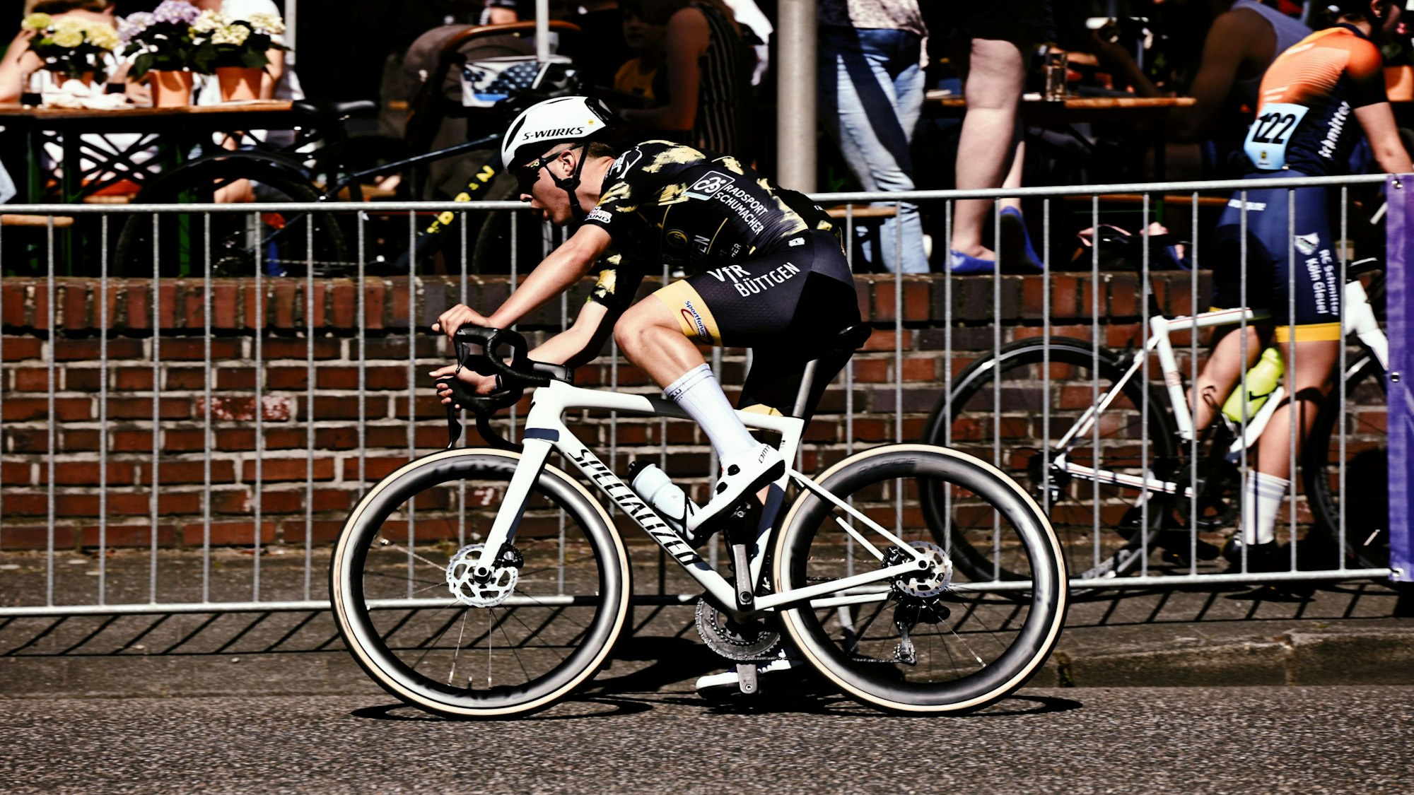 Mika Lohmar fährt auf einem weißen Rennrad an einer Absperrung vorbei.