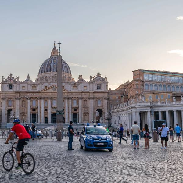Panoramic early morning scene at St Peter's square with police car and cicylists in foreground in Rome , Italy