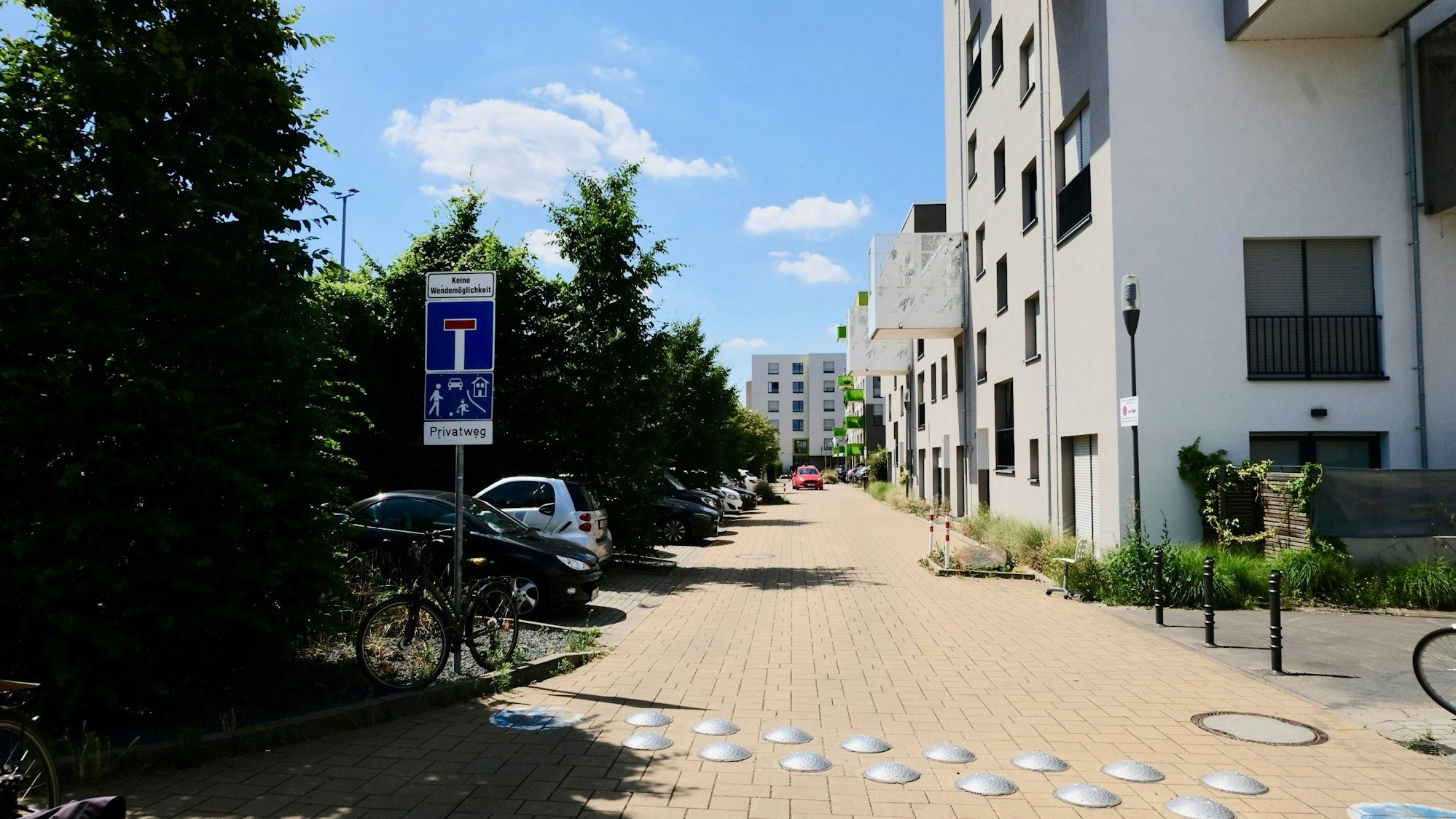 Ein Sackgassenschild steht am Beginn eines Weges, der durch Wohnblocks führt.