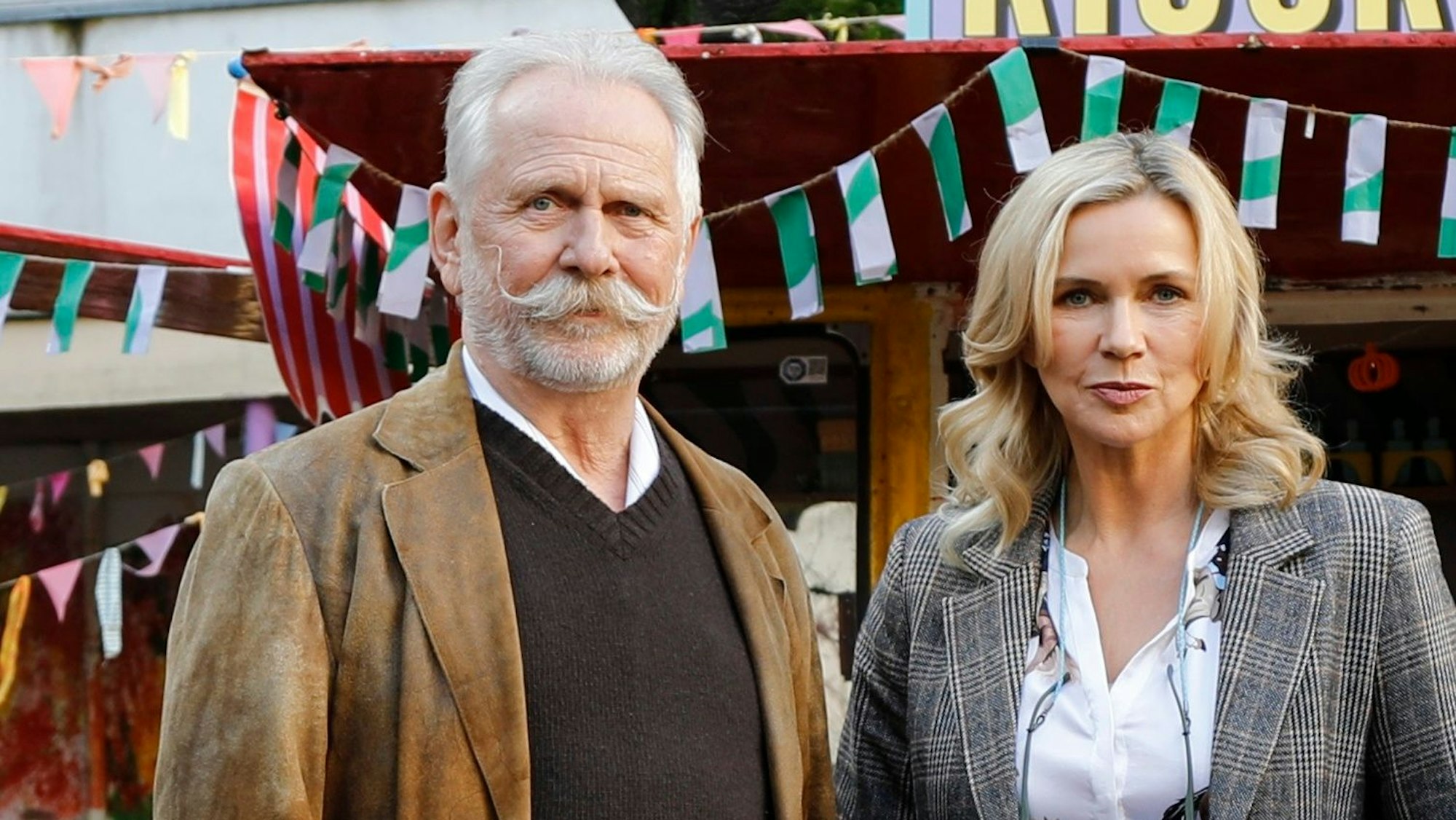 Ein Mann mit Schnäuzer steht neben einer Frau.