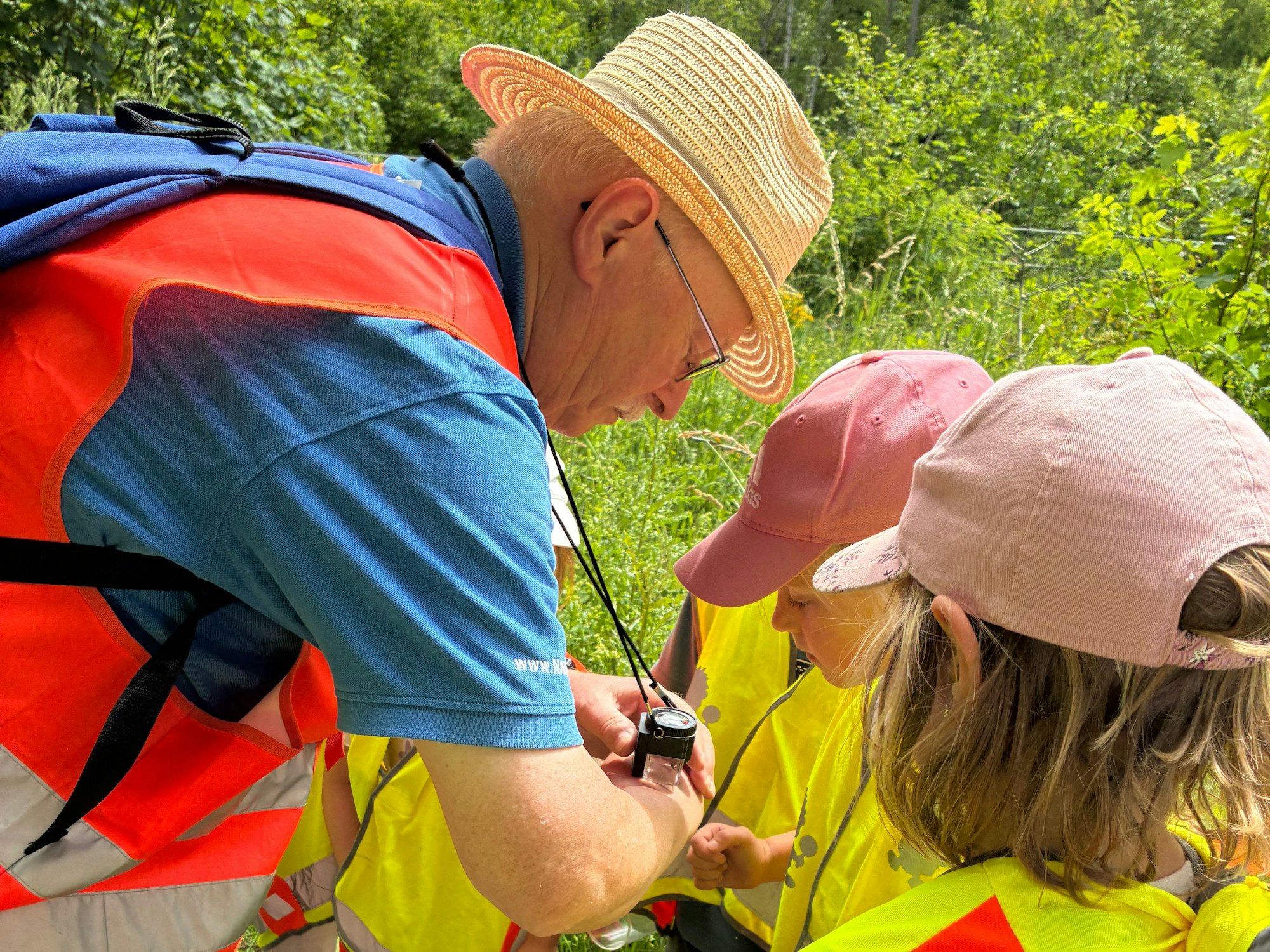 Arno Cymutta und die Kinder des Kita „Waldmeister“ betrachten eine Florfliege unter dem Lupenglas