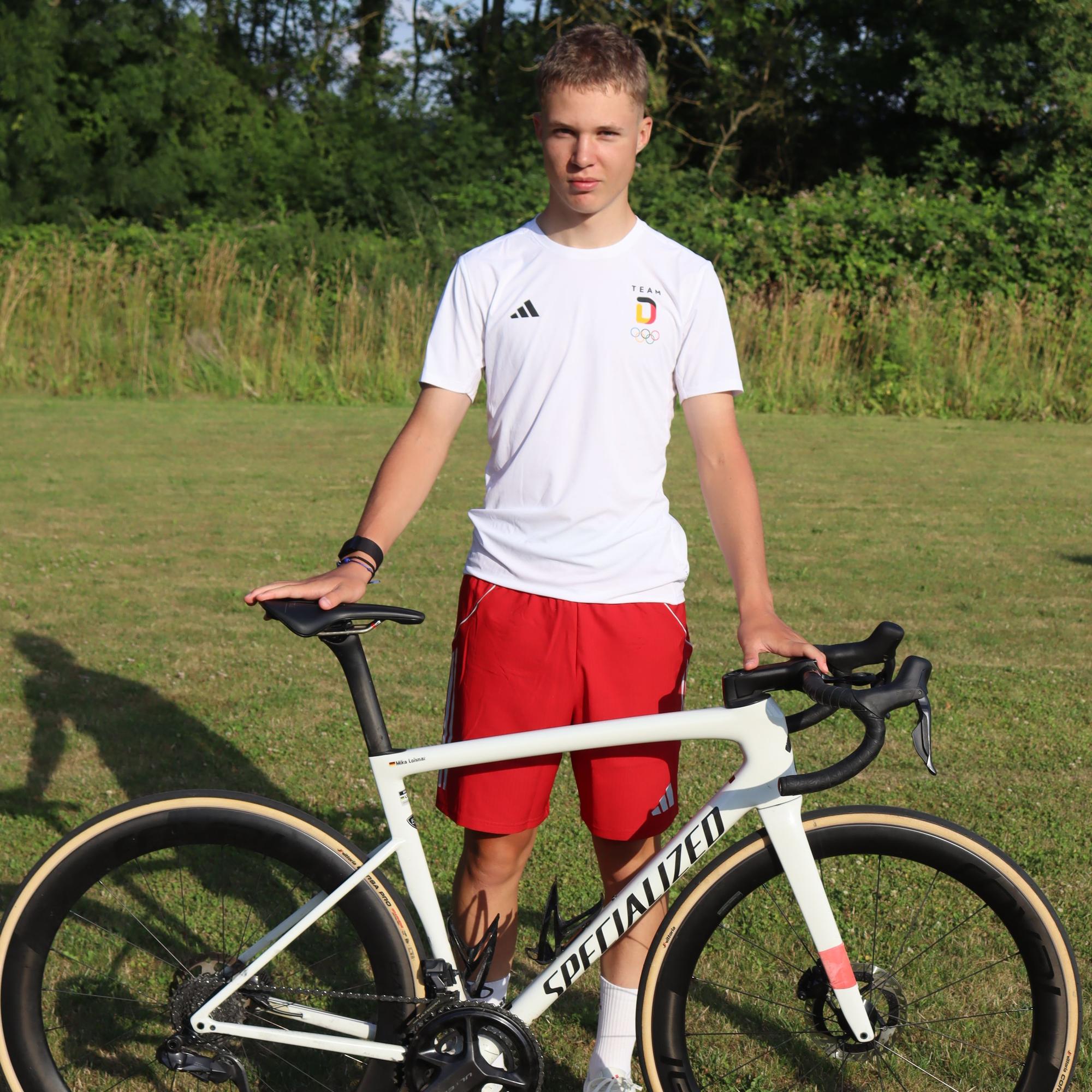 Rennradfahrer Mika Lohmar aus Flamersheim steht mit seinem Fahrrad auf einer Wiese.