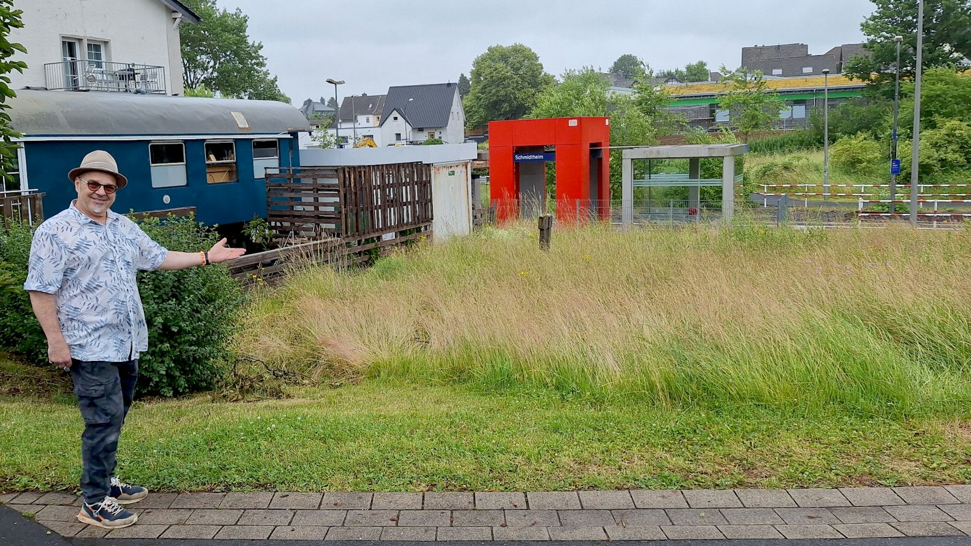 Benedetto Gentili steht an einer Wiese, im Hintergrund ist der Bahnhof Schmidtheim zu sehen.