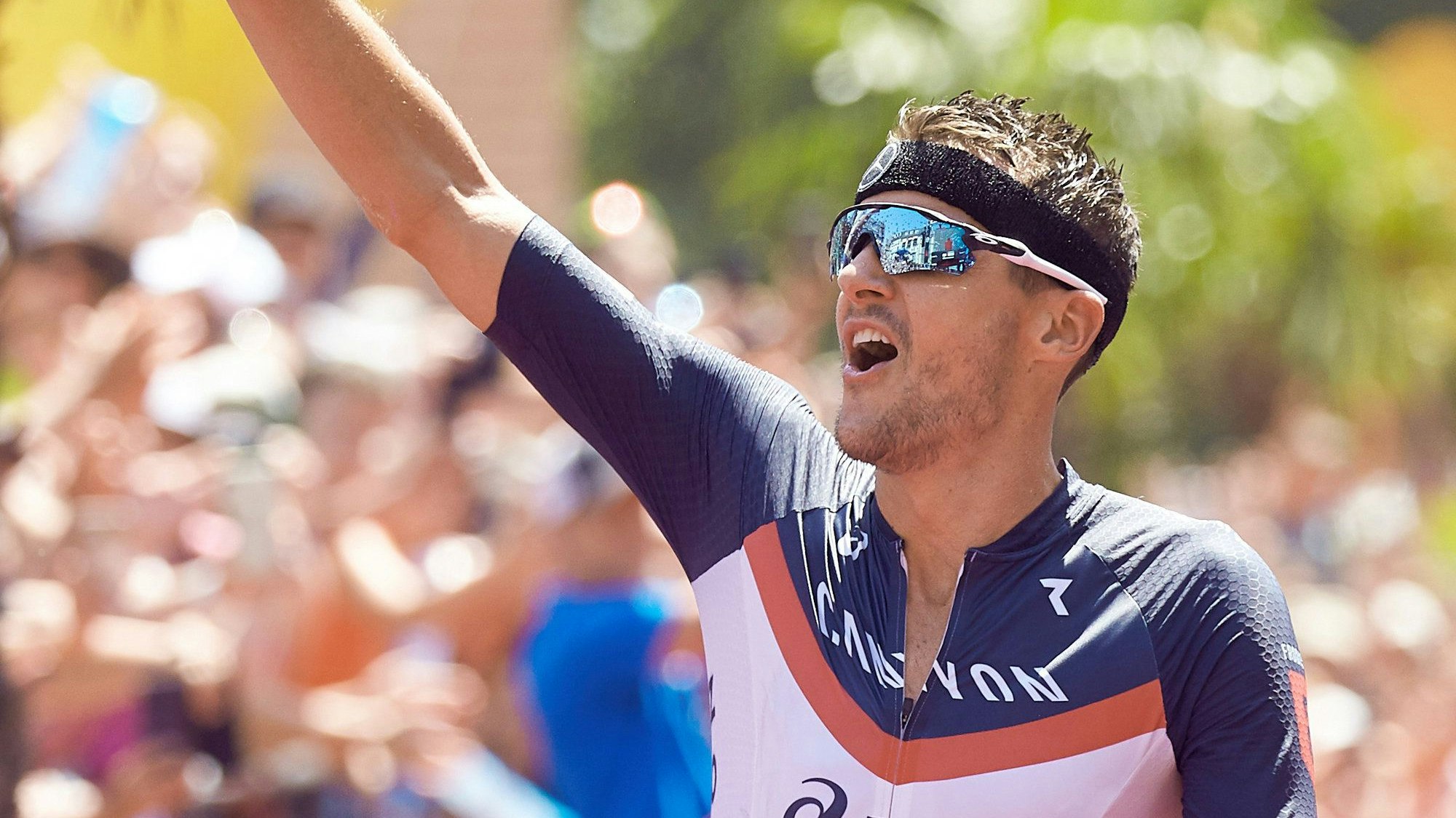 Jan Frodeno aus Deutschland jubelt beim Zieleinlauf bei der Ironman Europameisterschaft 2019. Er trägt einen Rennanzug mit dem Logo von Ryzon.
